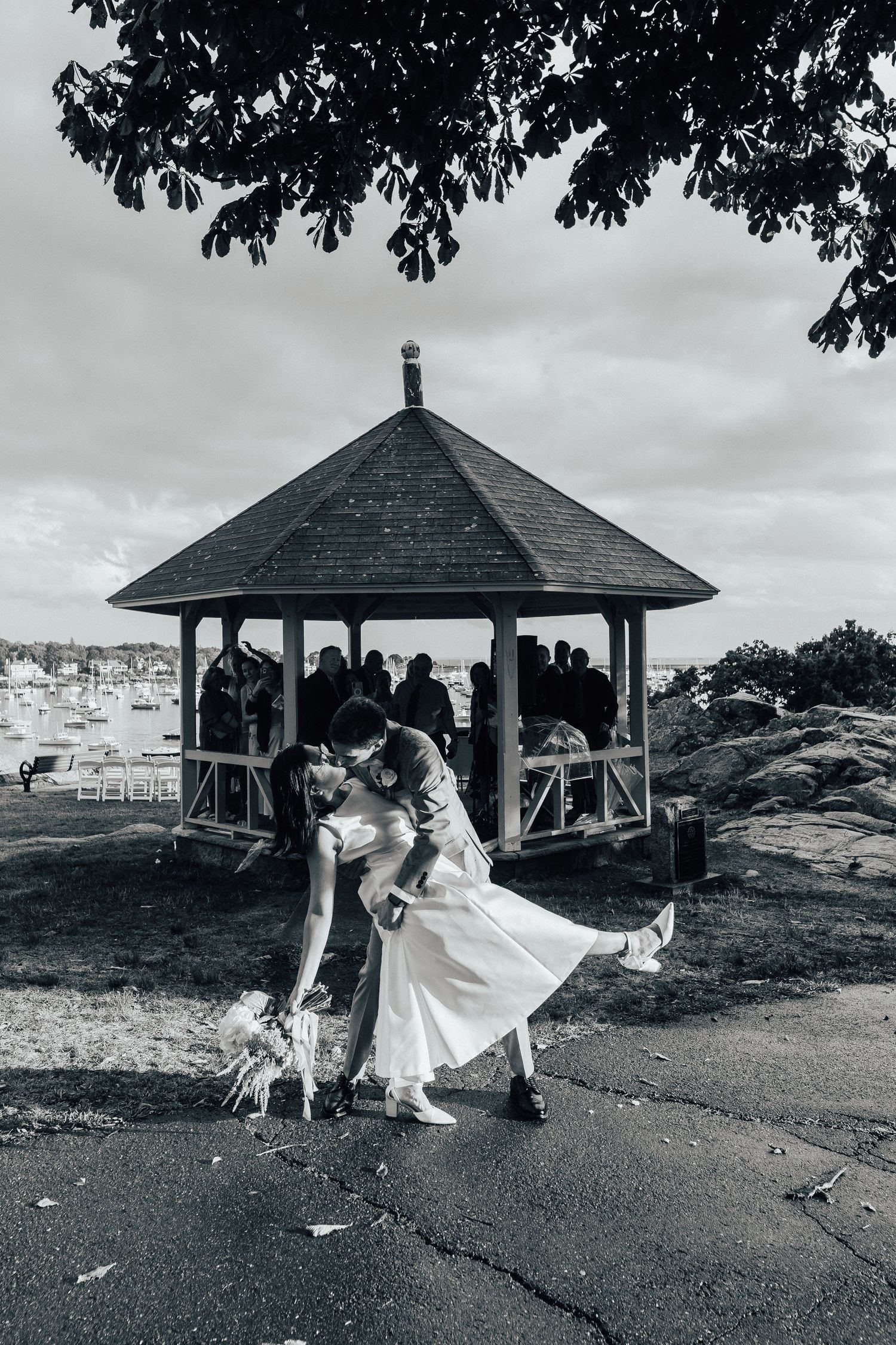 A romantic dance pose in a gazebo overlooking a scenic coastal view in black and white.