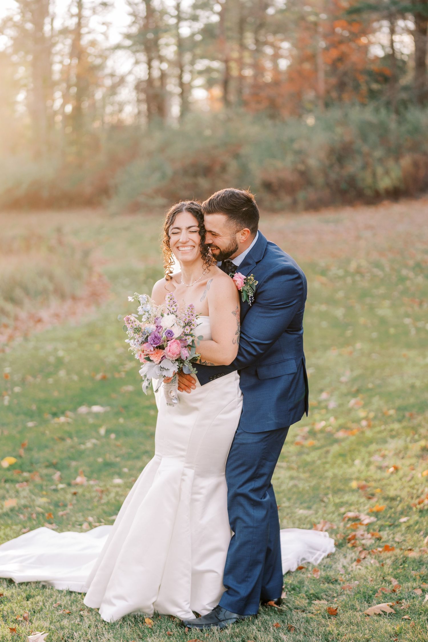 A couple shares romantic moments in a fall forest setting wearing wedding attire.