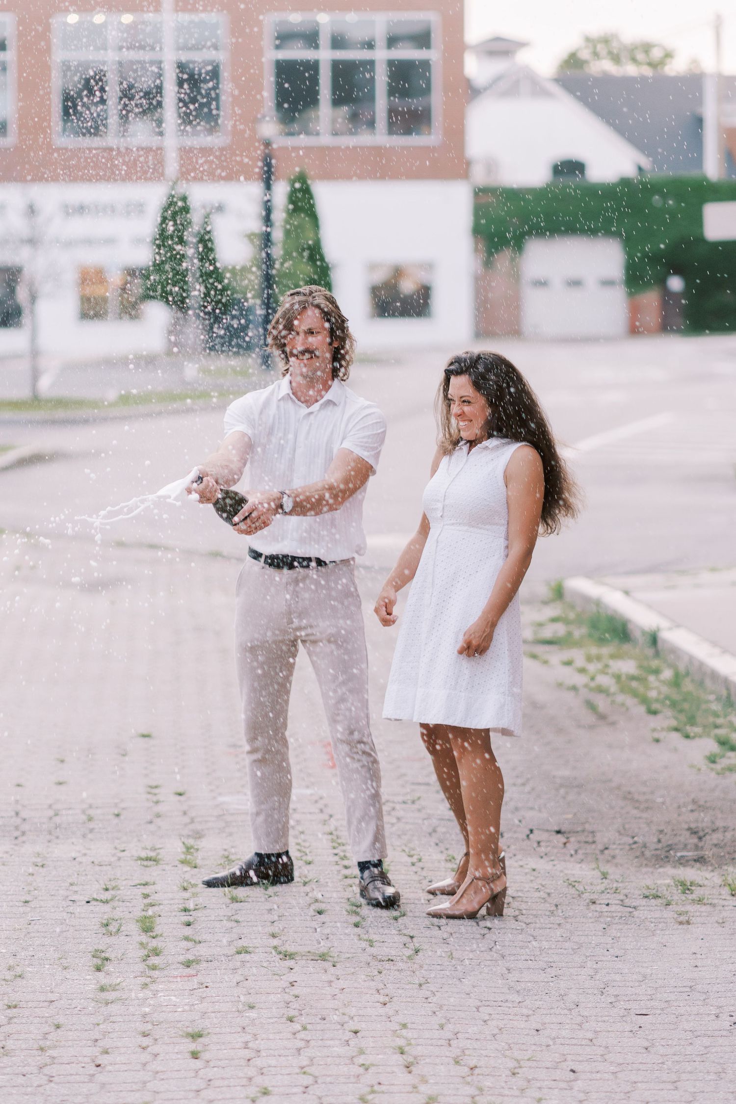 Playful couple having fun with water splashes on a cobblestone street.
