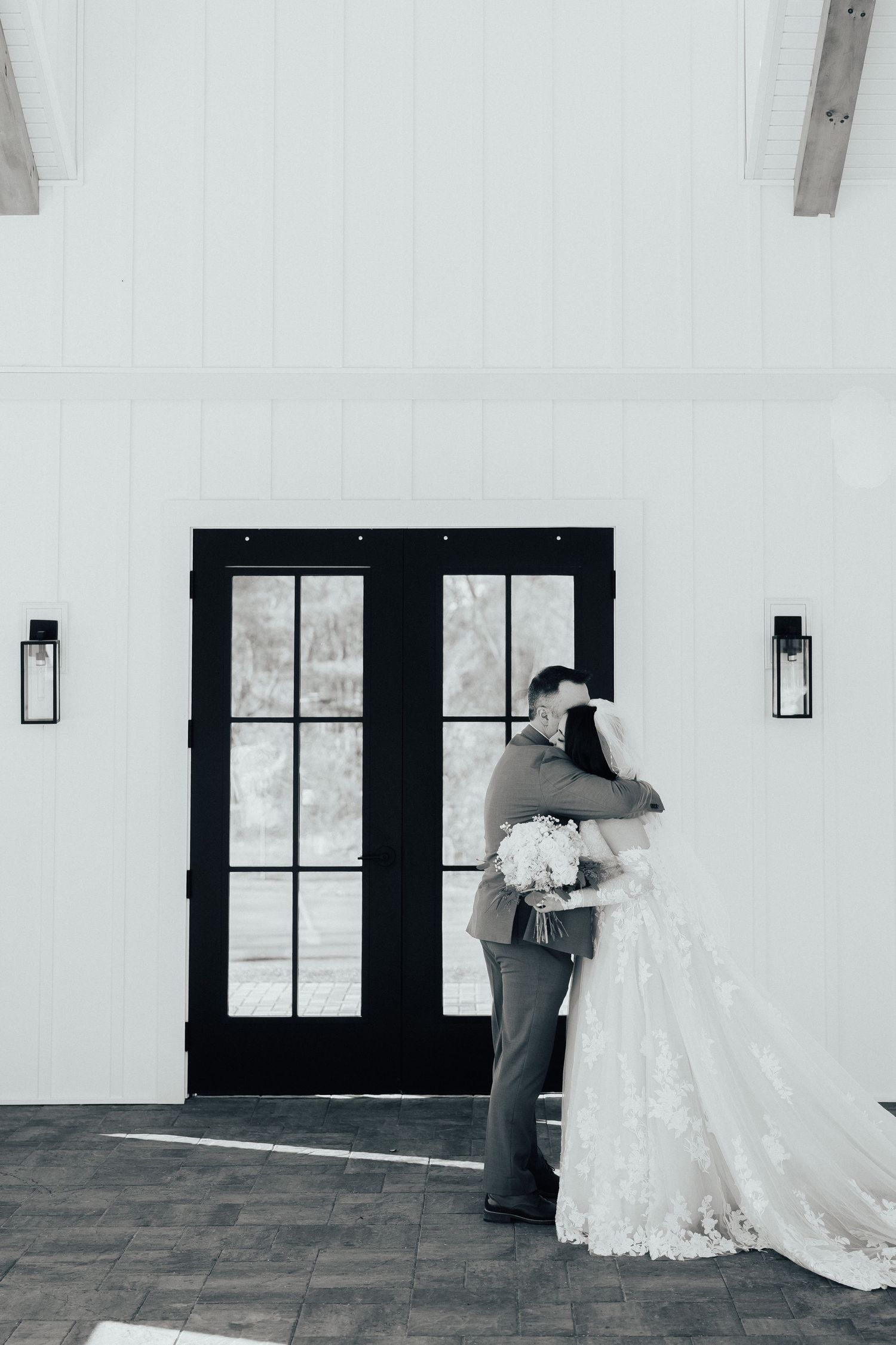 A series of black and white photos showing a couple in wedding attire sharing an intimate moment against a wall.