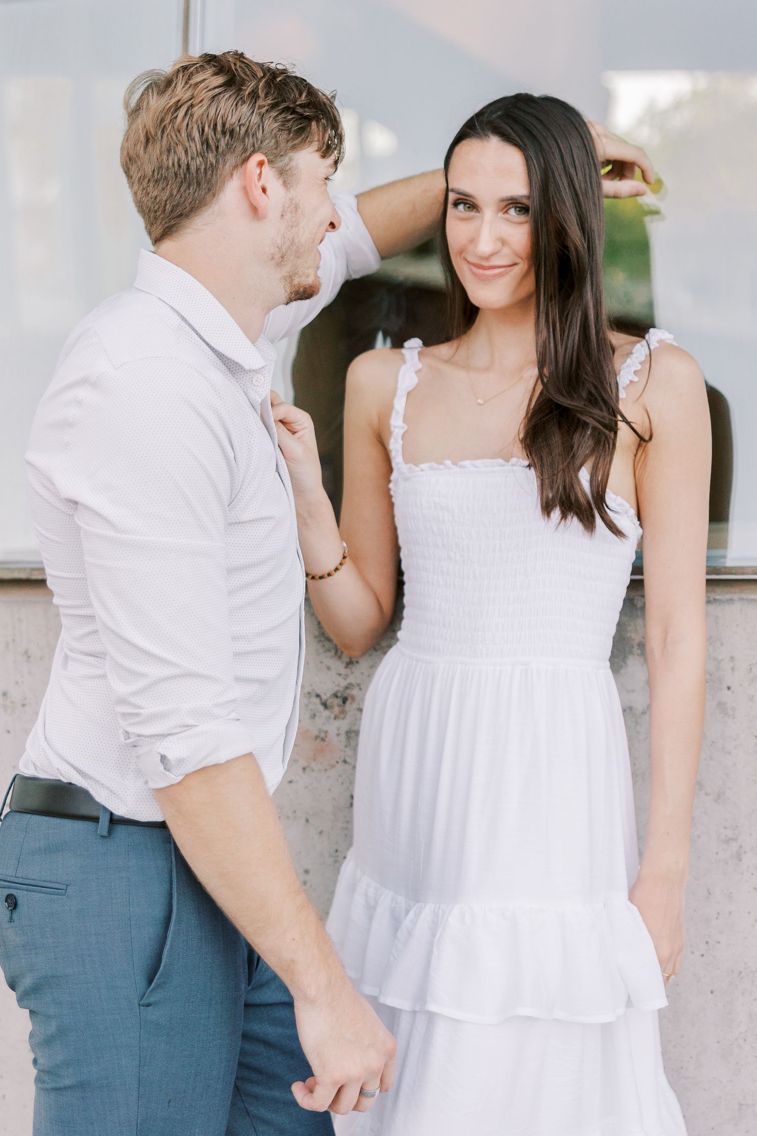 Romantic couple in white and blue outfits share tender moments against a light background in a photo series.