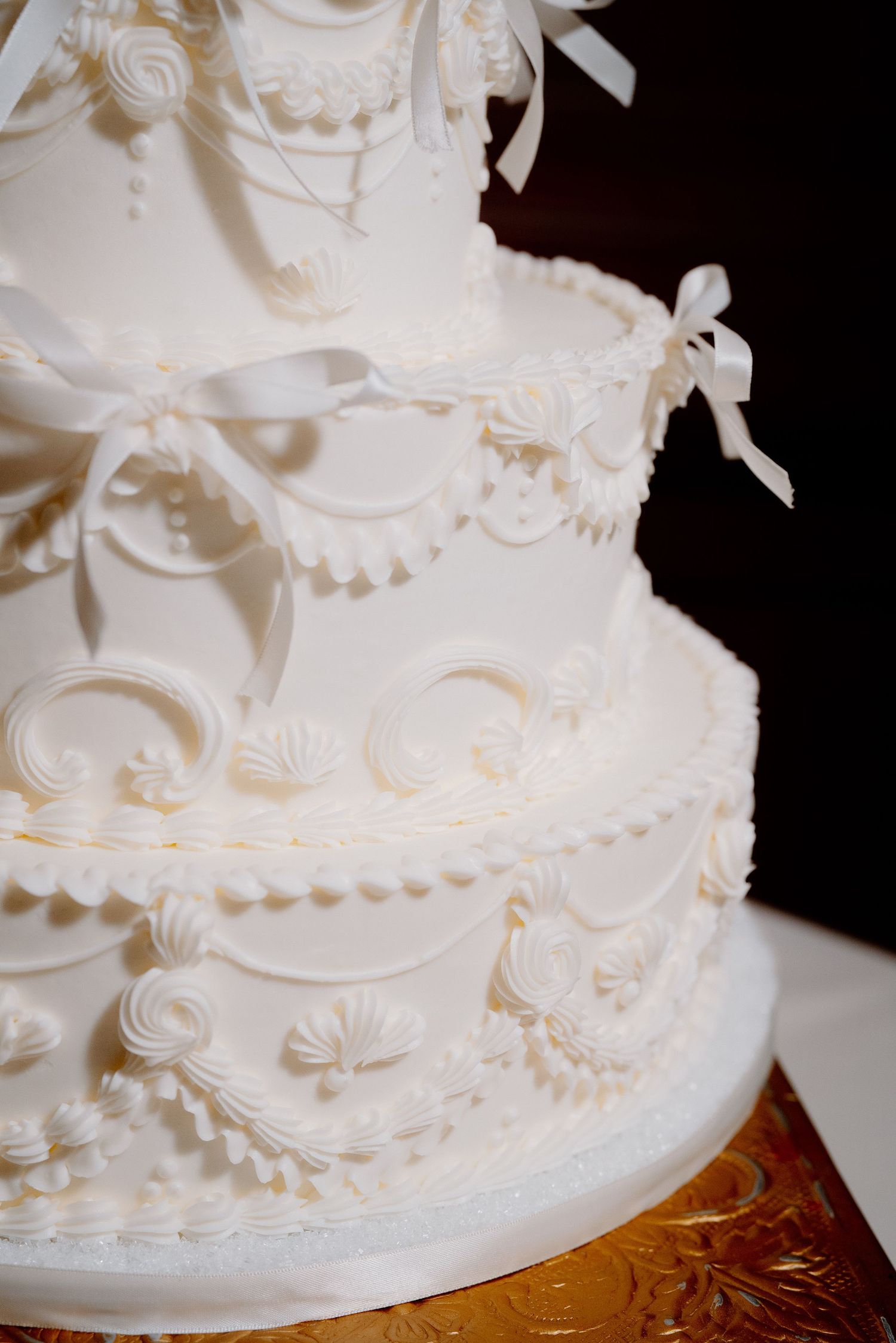 Close-up view of an elegant white wedding cake with delicate piping details and ornate decorative patterns.