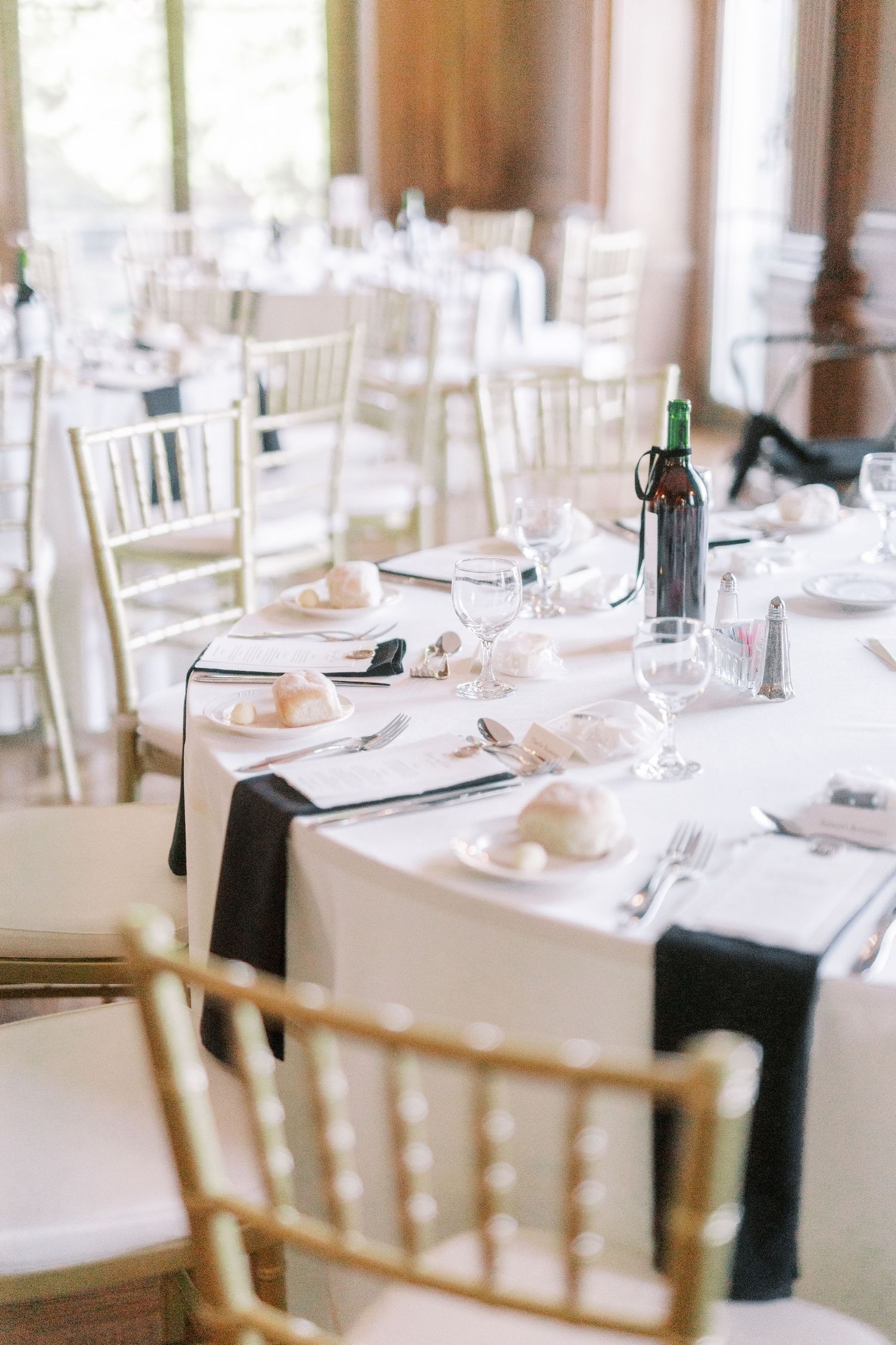 Elegant wedding reception tables set with white linens, chiavari chairs and formal place settings.