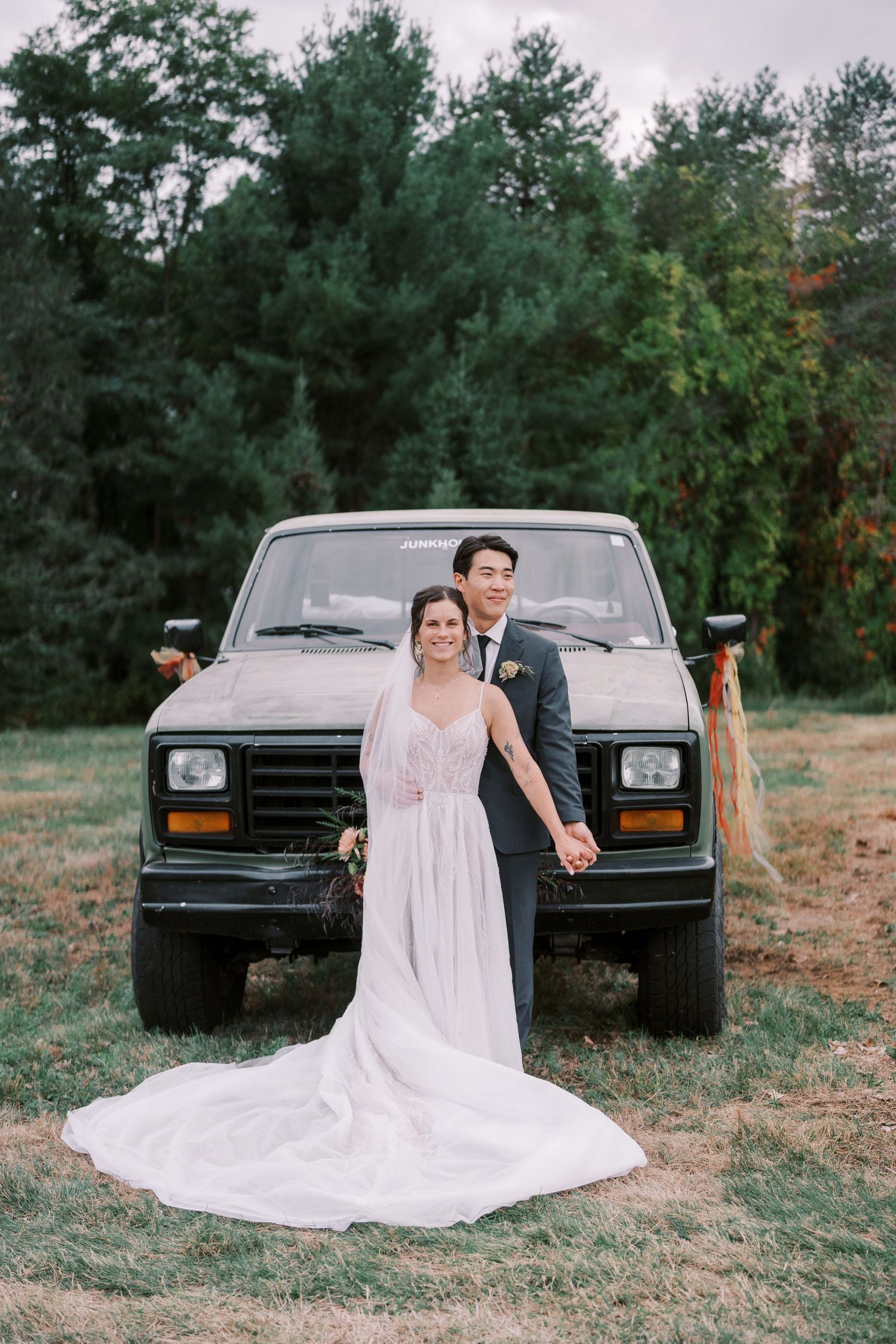 A classic black pickup truck serves as a backdrop for outdoor wedding photos on a grassy field.
