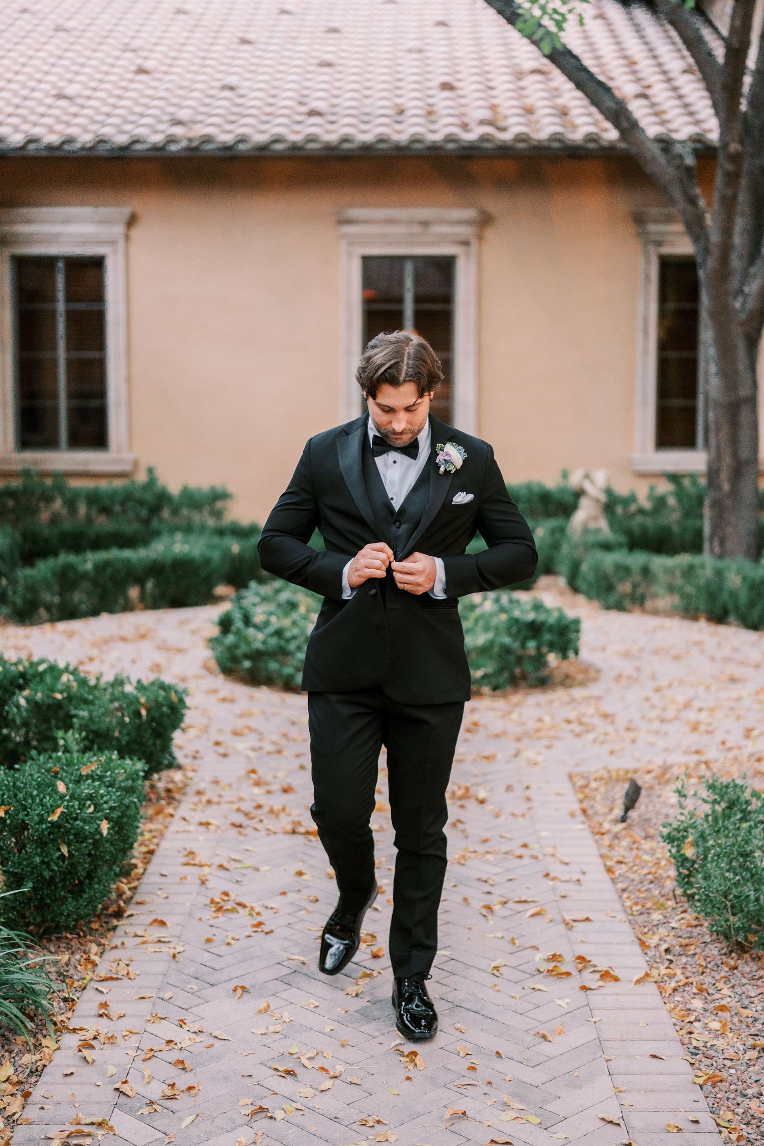 Four sequential photos show someone in a black tuxedo playfully running and jumping on a leaf-covered pathway.