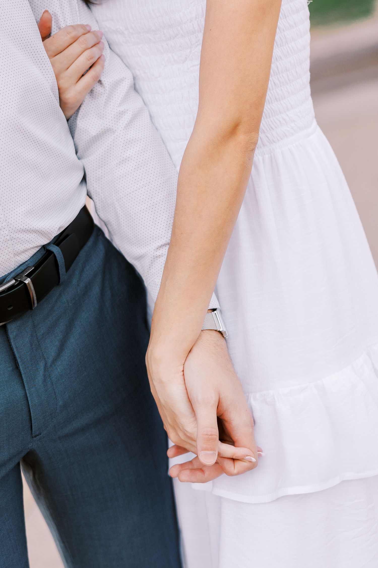 Close-up of hands adjusting a white dress sleeve against a dark background.
