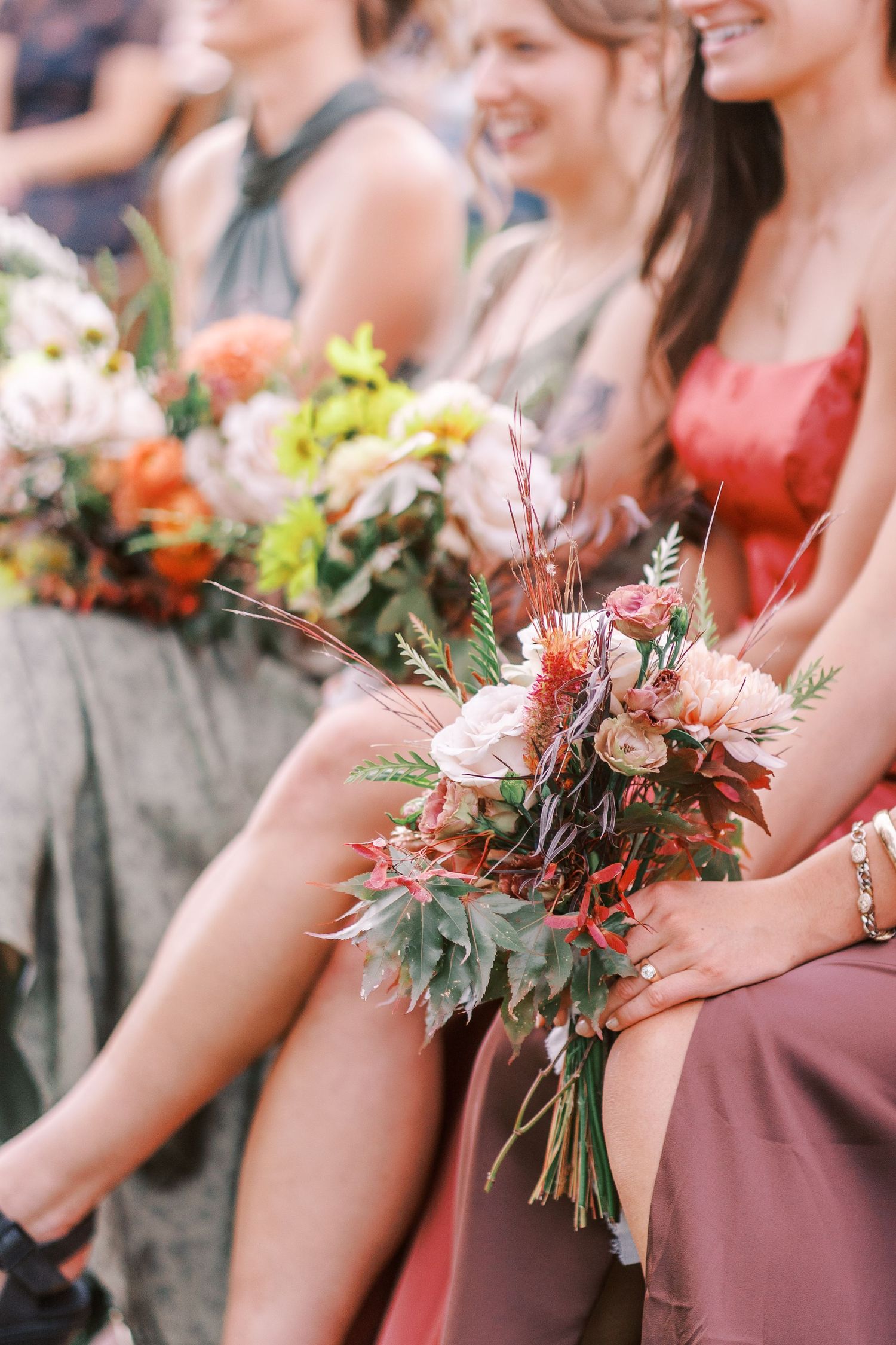Bridesmaids holding vibrant coral and green floral bouquets.
