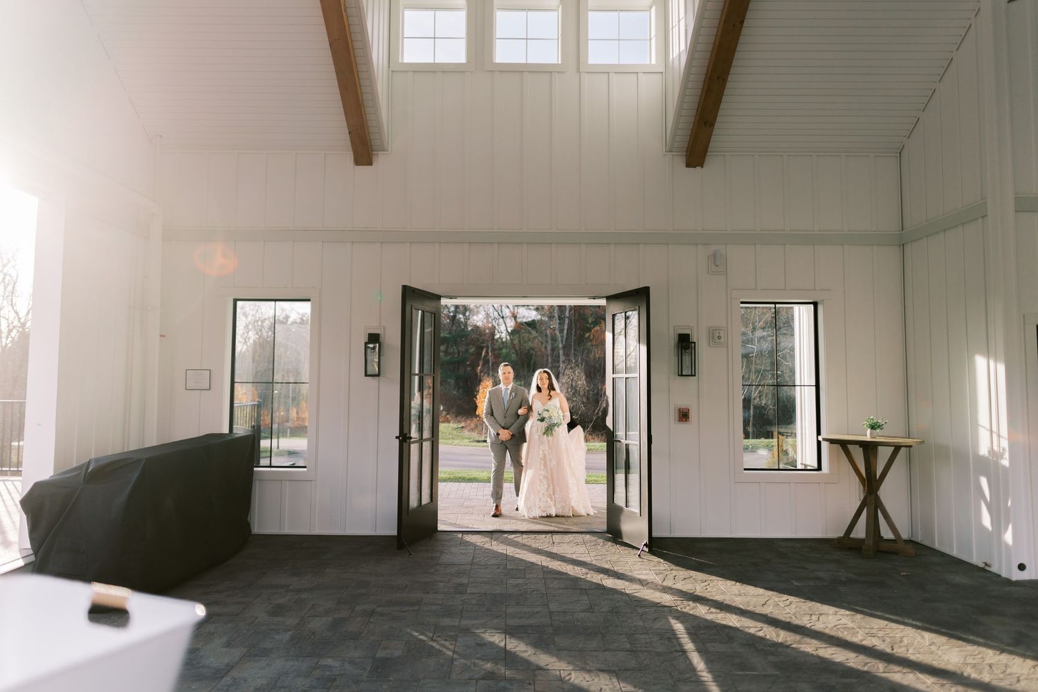 A bright, minimalist interior space with white walls, exposed beams, and large windows letting in natural light.