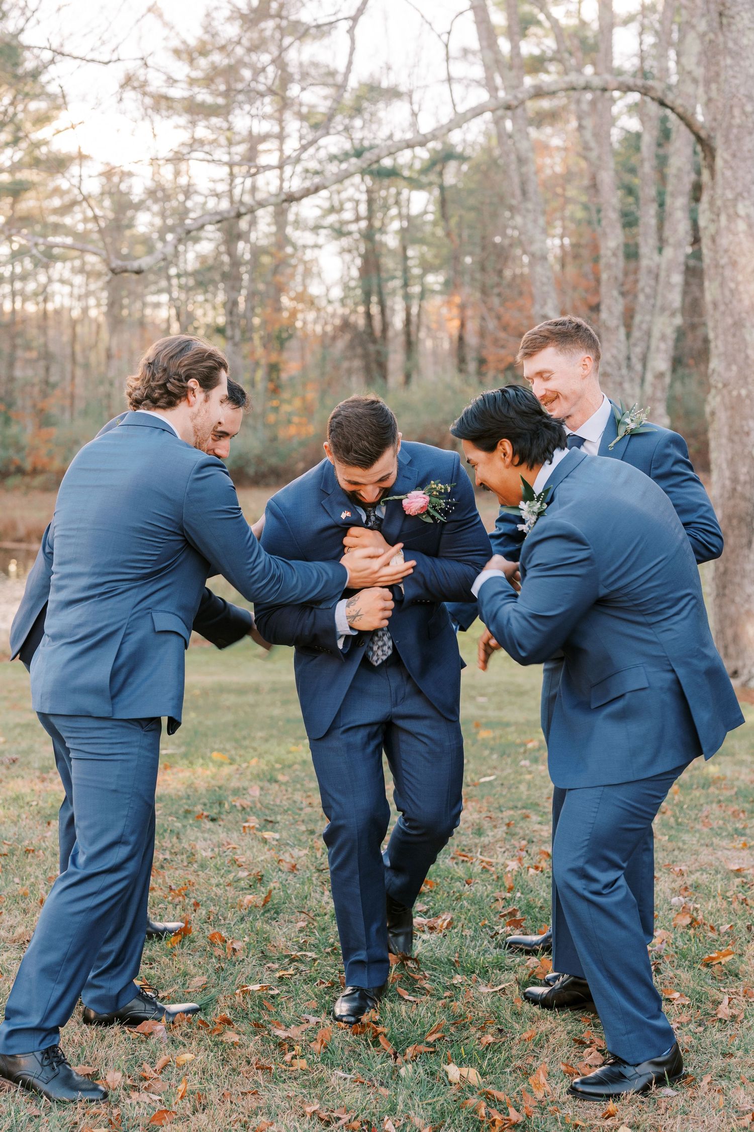 Wedding party in navy blue suits playfully poses in a sequence of falling domino-style photos in an autumn setting.