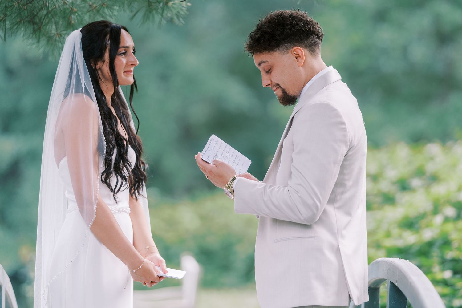 Couple exchanging vows on a wooden deck surrounded by trees.