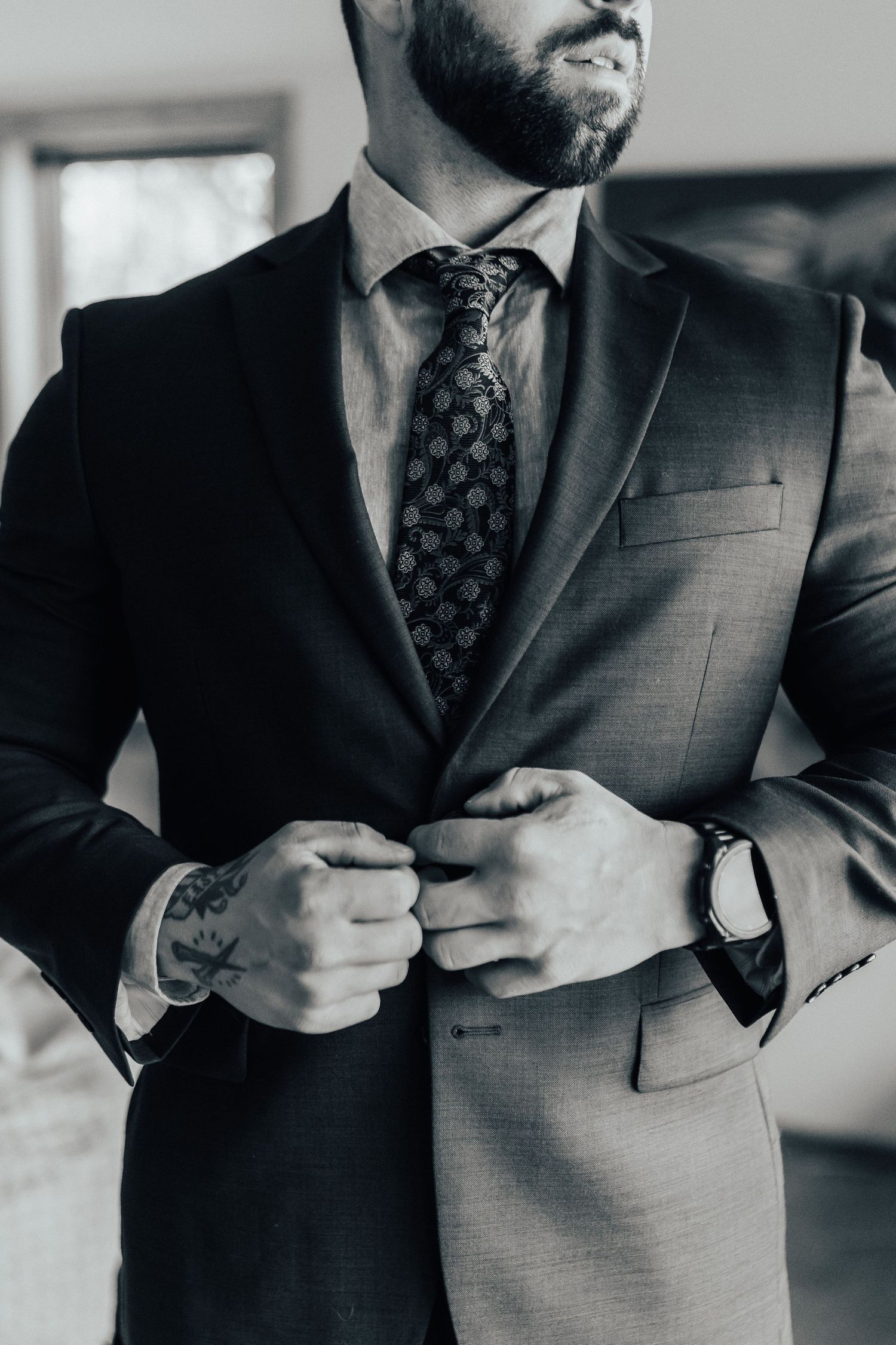 Close-up black and white photo series showing details of a man buttoning up a formal suit jacket.