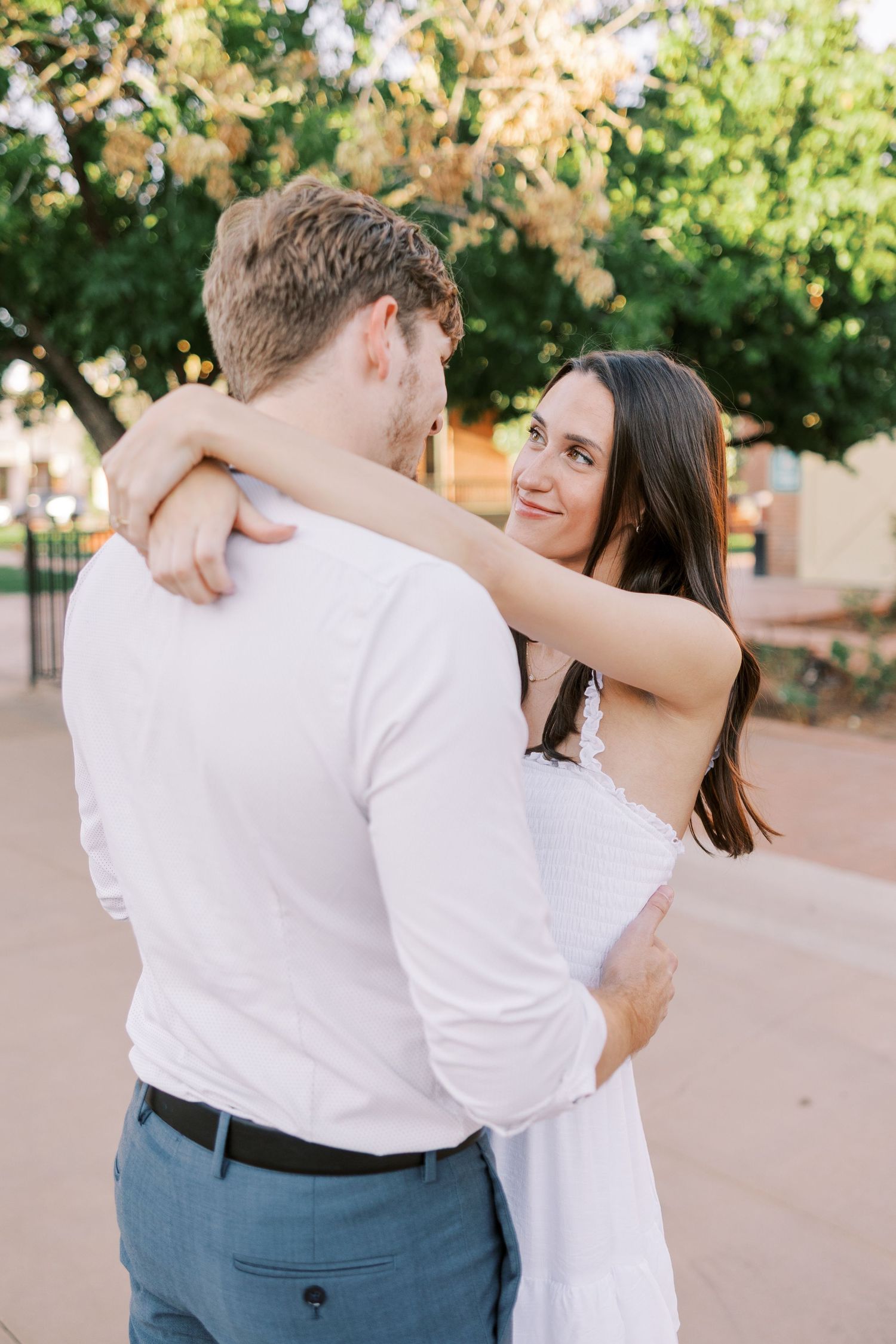 Romantic couple embracing and dancing together on a paved outdoor pathway.