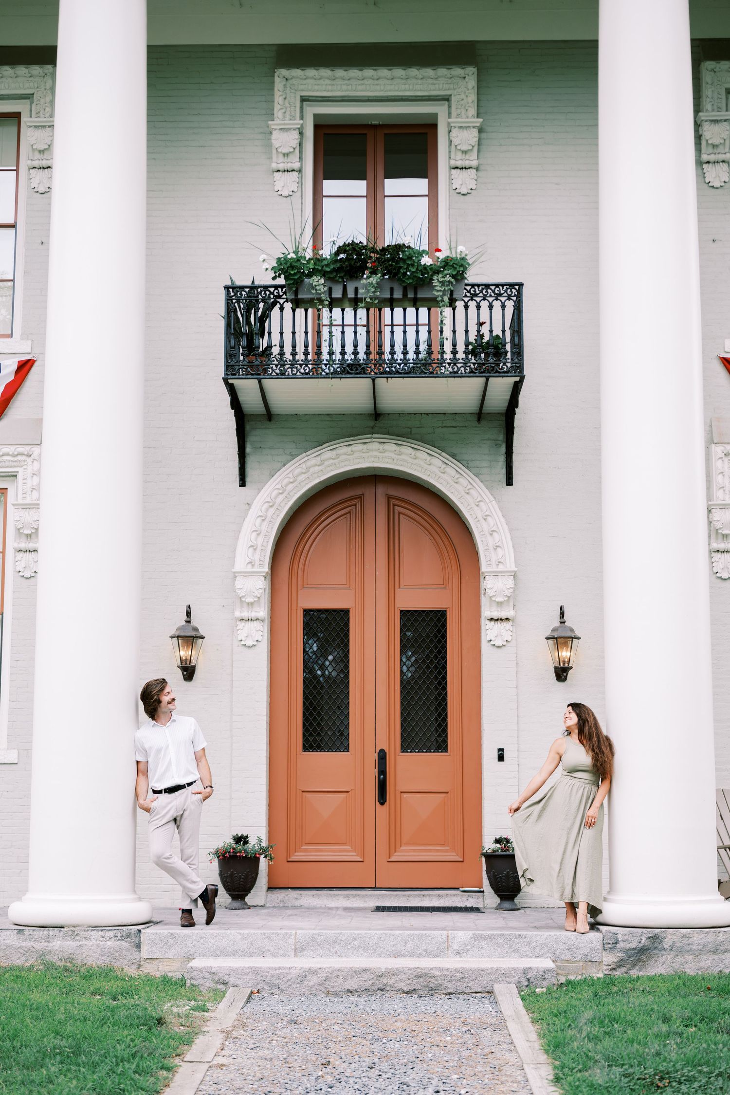 A classic white mansion entrance with tall columns and ornate wooden double doors.