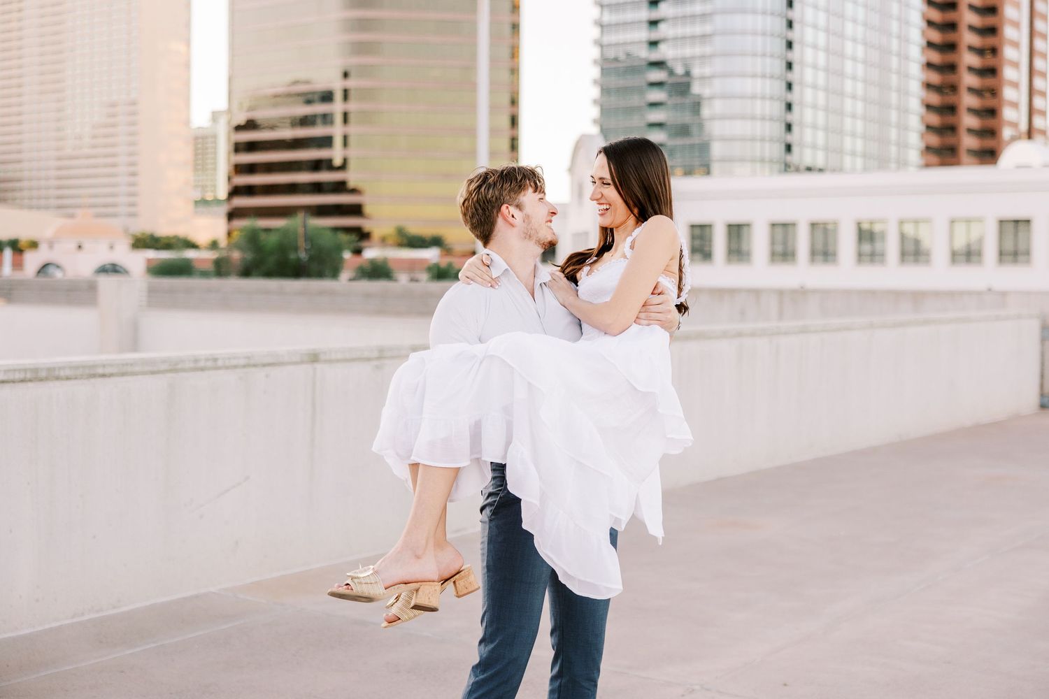 Couple dancing and twirling in an urban setting with city buildings in the background.