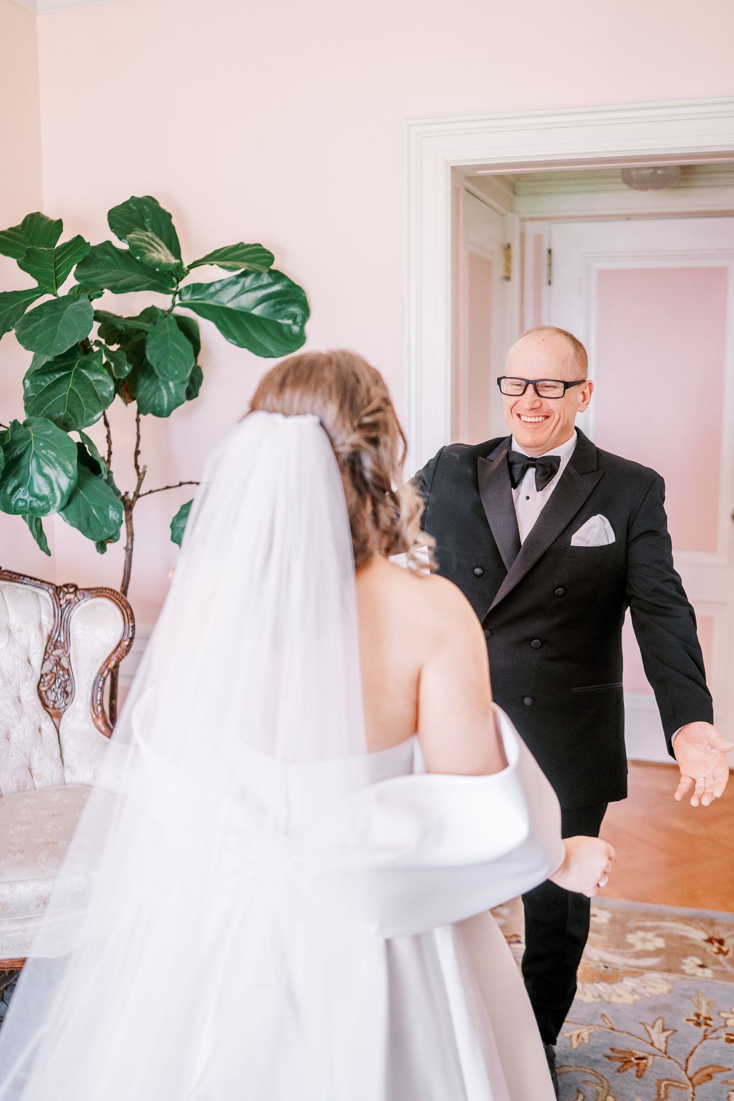 A heartwarming first look moment between a bride in white and an older gentleman in a black suit.