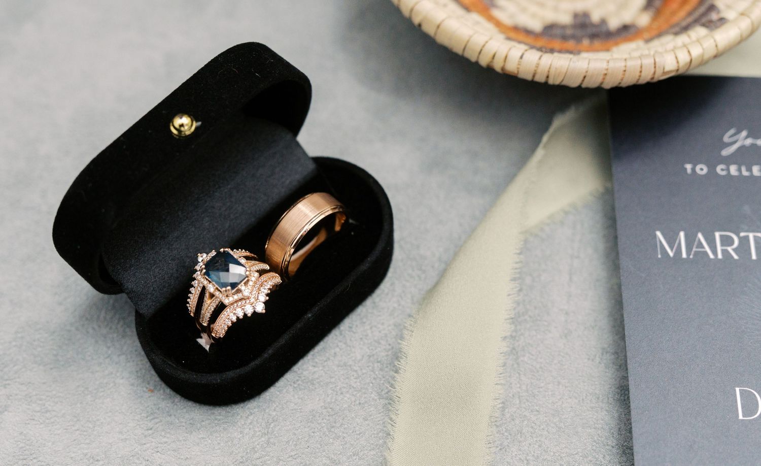 Rose gold engagement ring with diamond solitaire shown in black velvet ring box atop gray surface.