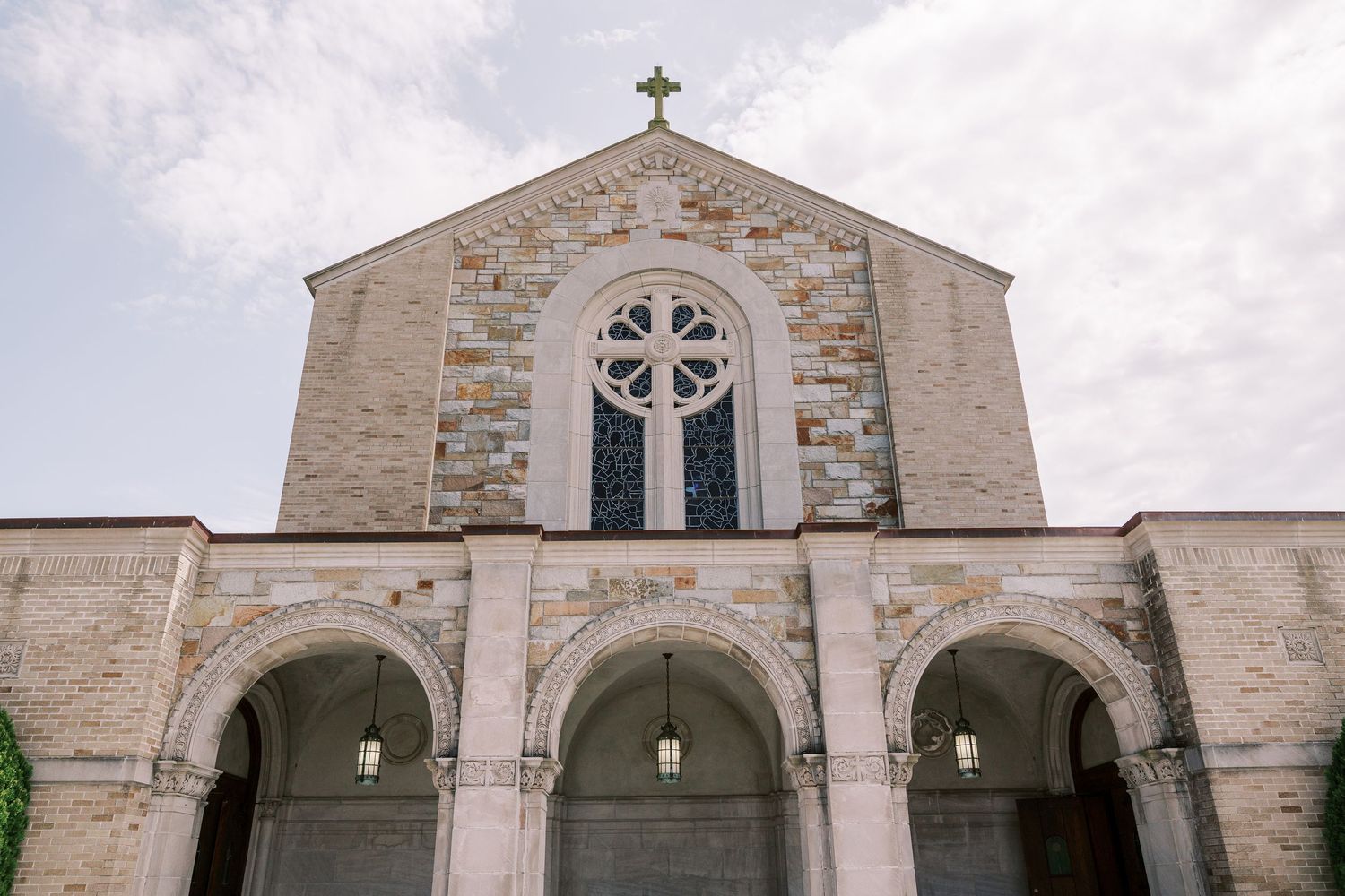 Traditional stone church facade with cross details and multiple arched entranceways.