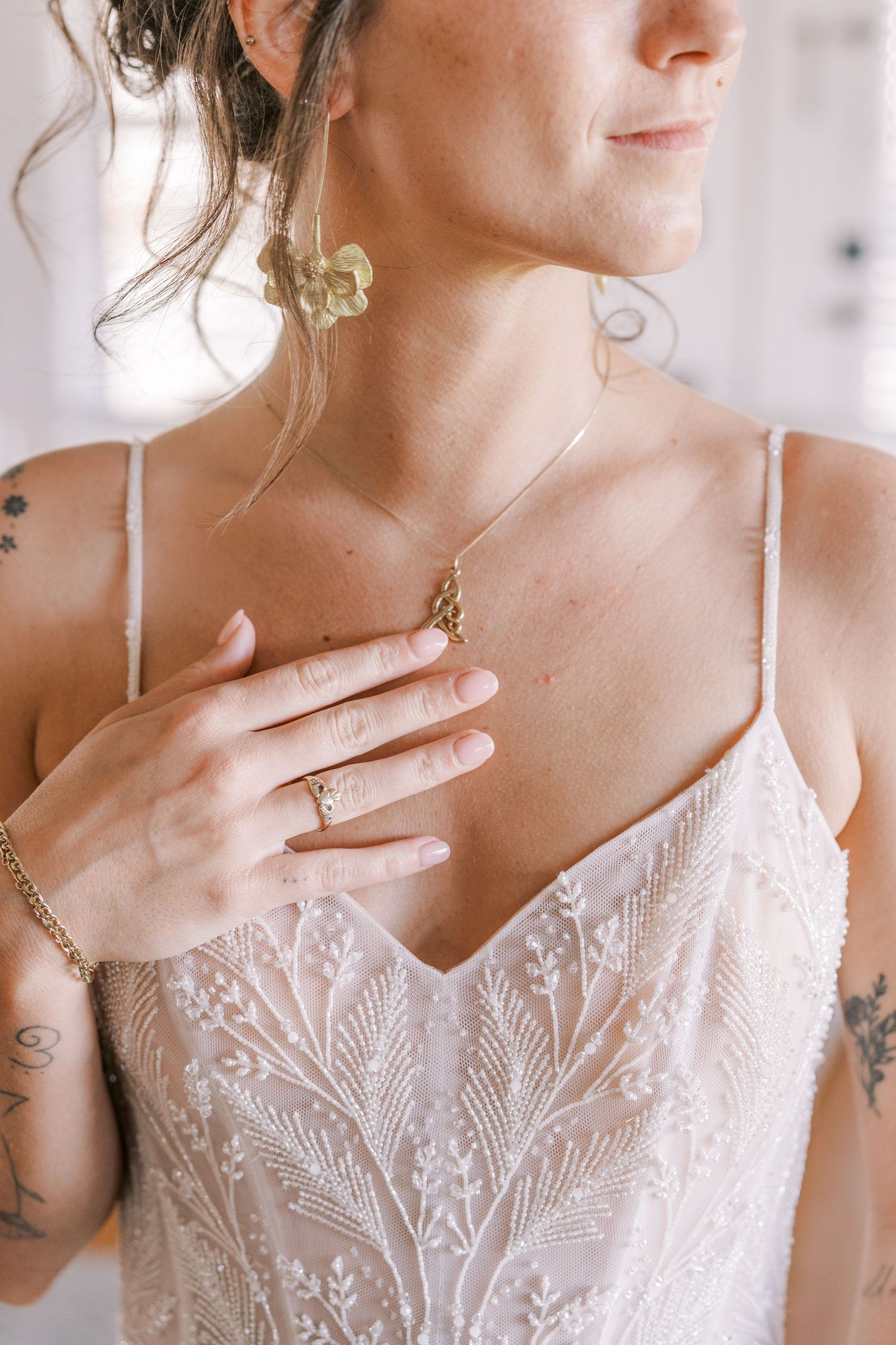 Close-up detail of delicate white lace wedding dress bodice with spaghetti straps and vintage-style beaded necklace.