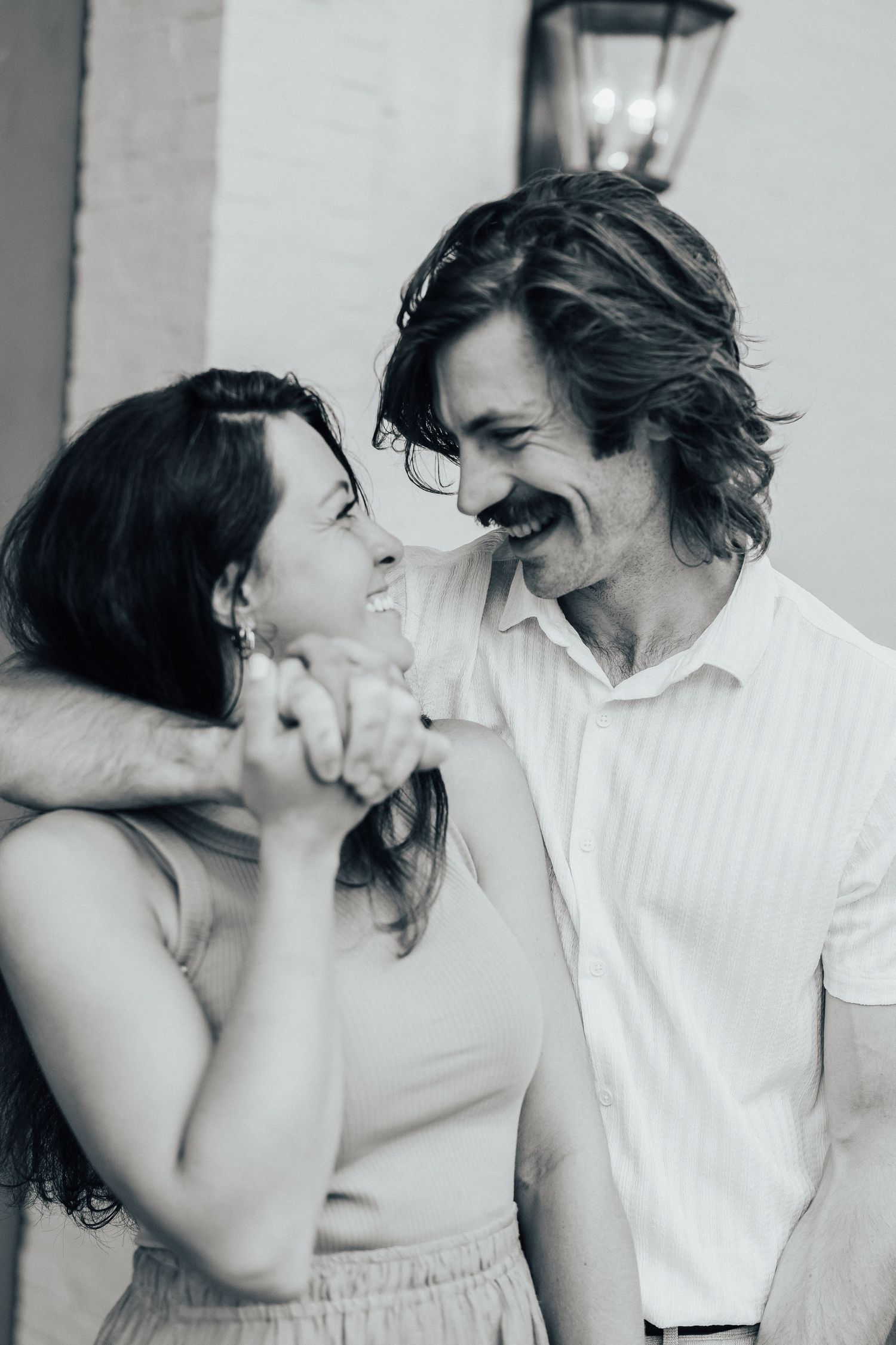 Two people share intimate moments in black and white photography against a light background.