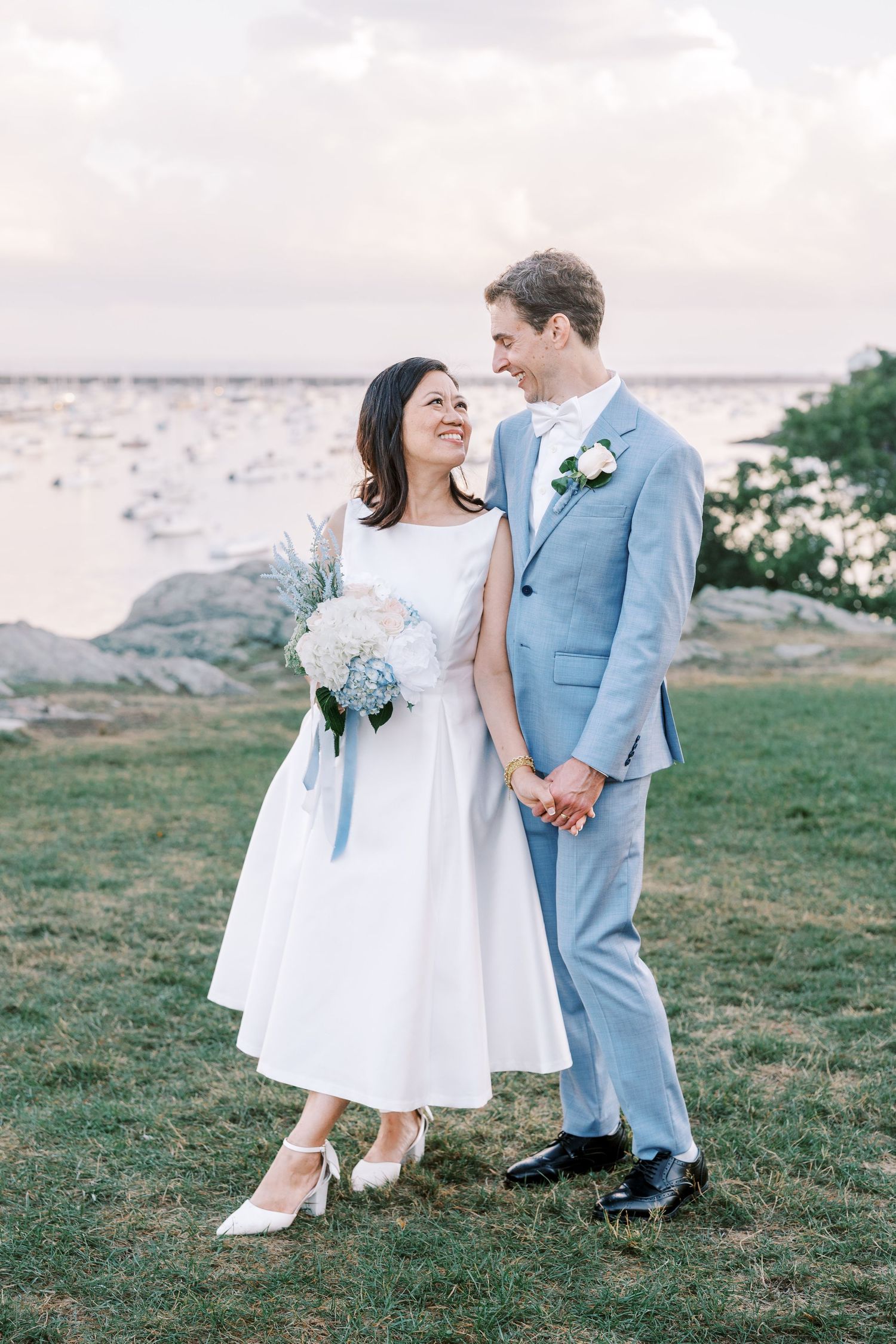 A seaside wedding photo series with a couple in light blue suit and white dress against an ocean backdrop.