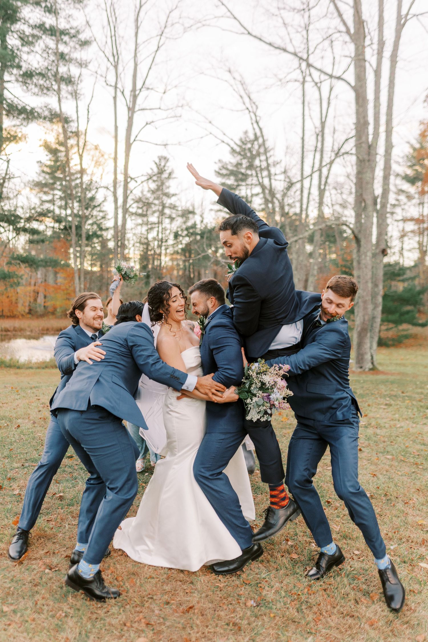 A fun wedding party sequence shows groomsmen pretending to tackle and fall over in a playful outdoor autumn photoshoot.
