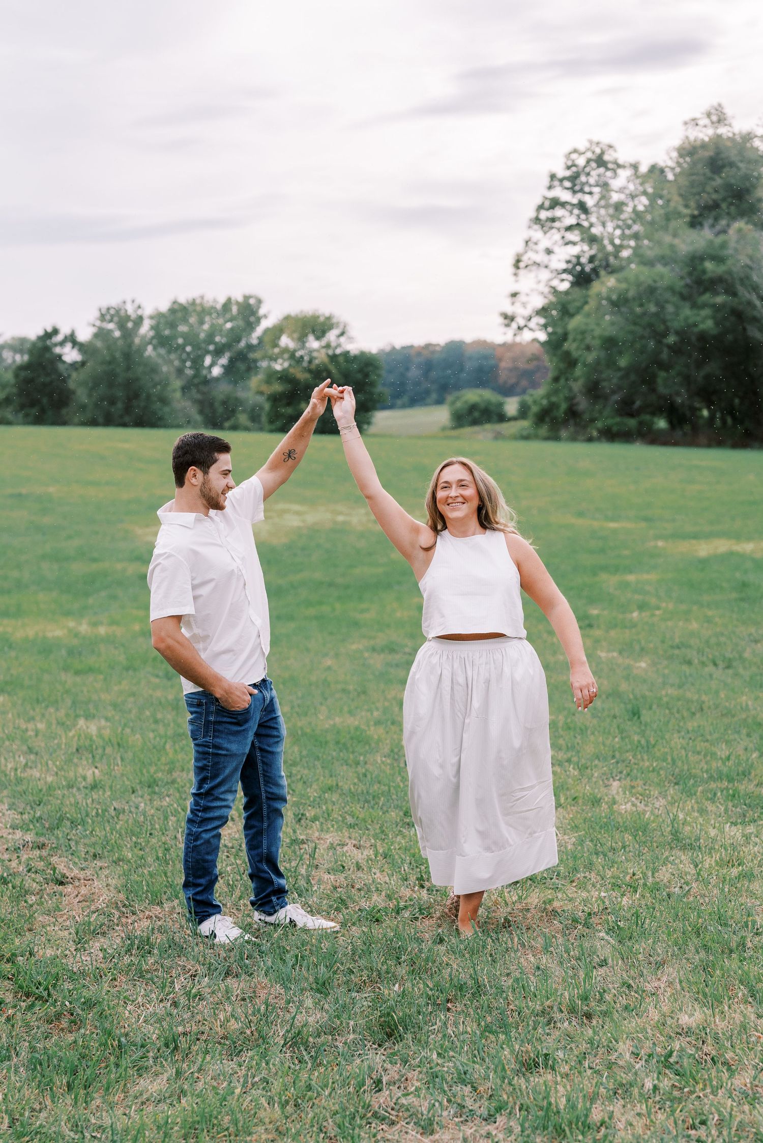 A couple dancing and twirling together in a sunny green field.