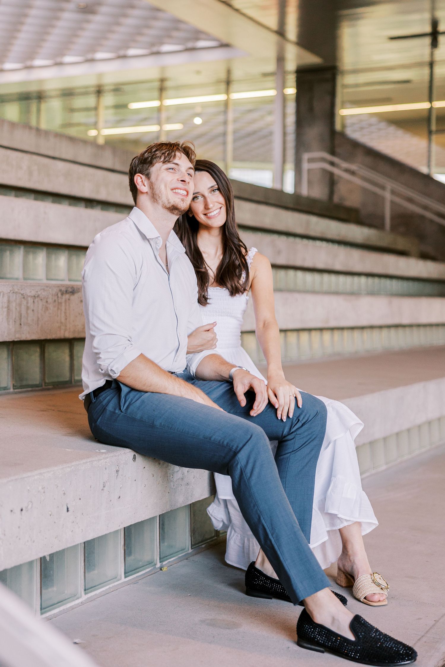 Couple relaxing on modern architectural steps with glass windows.