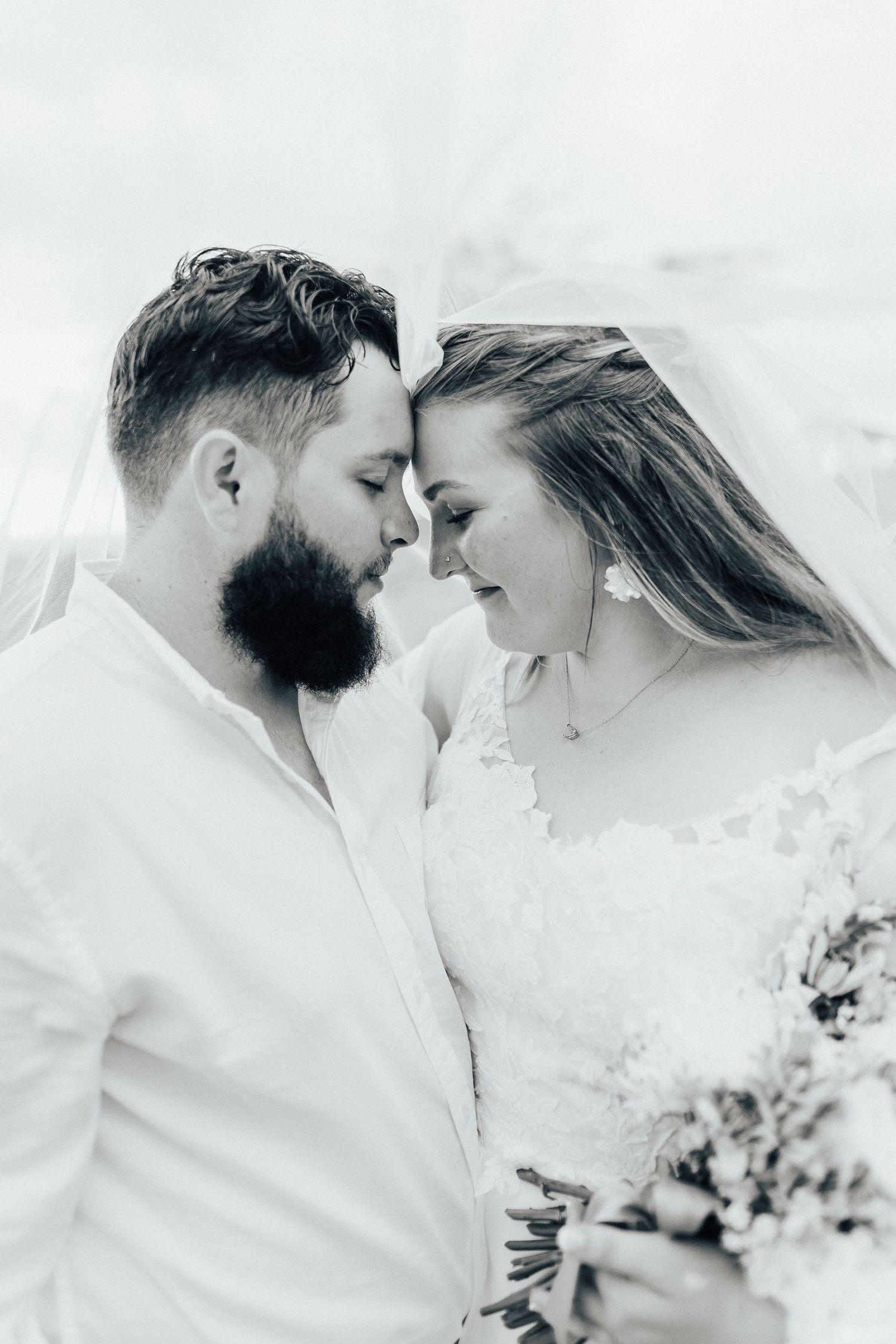 An intimate black and white portrait of a couple sharing a tender moment on their wedding day.