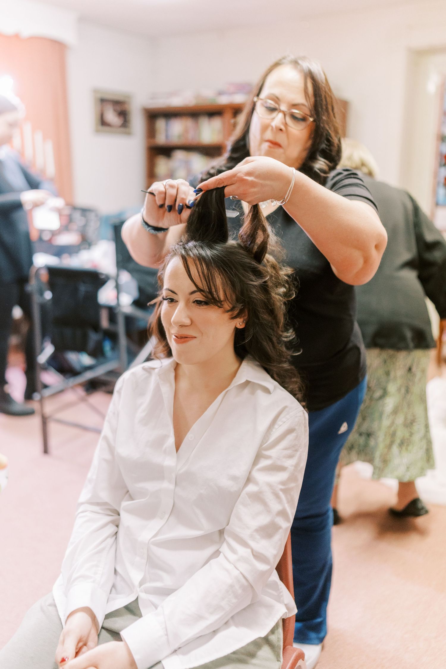Getting ready on wedding day morning with hair styling in progress in a bright salon setting.