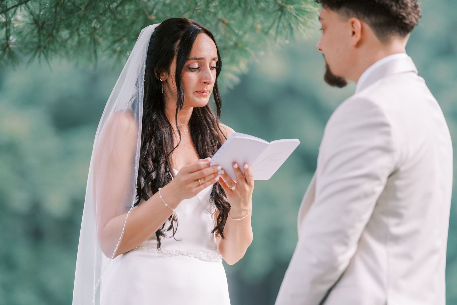 A wedding ceremony moment with a couple exchanging vows outdoors against a nature backdrop.
