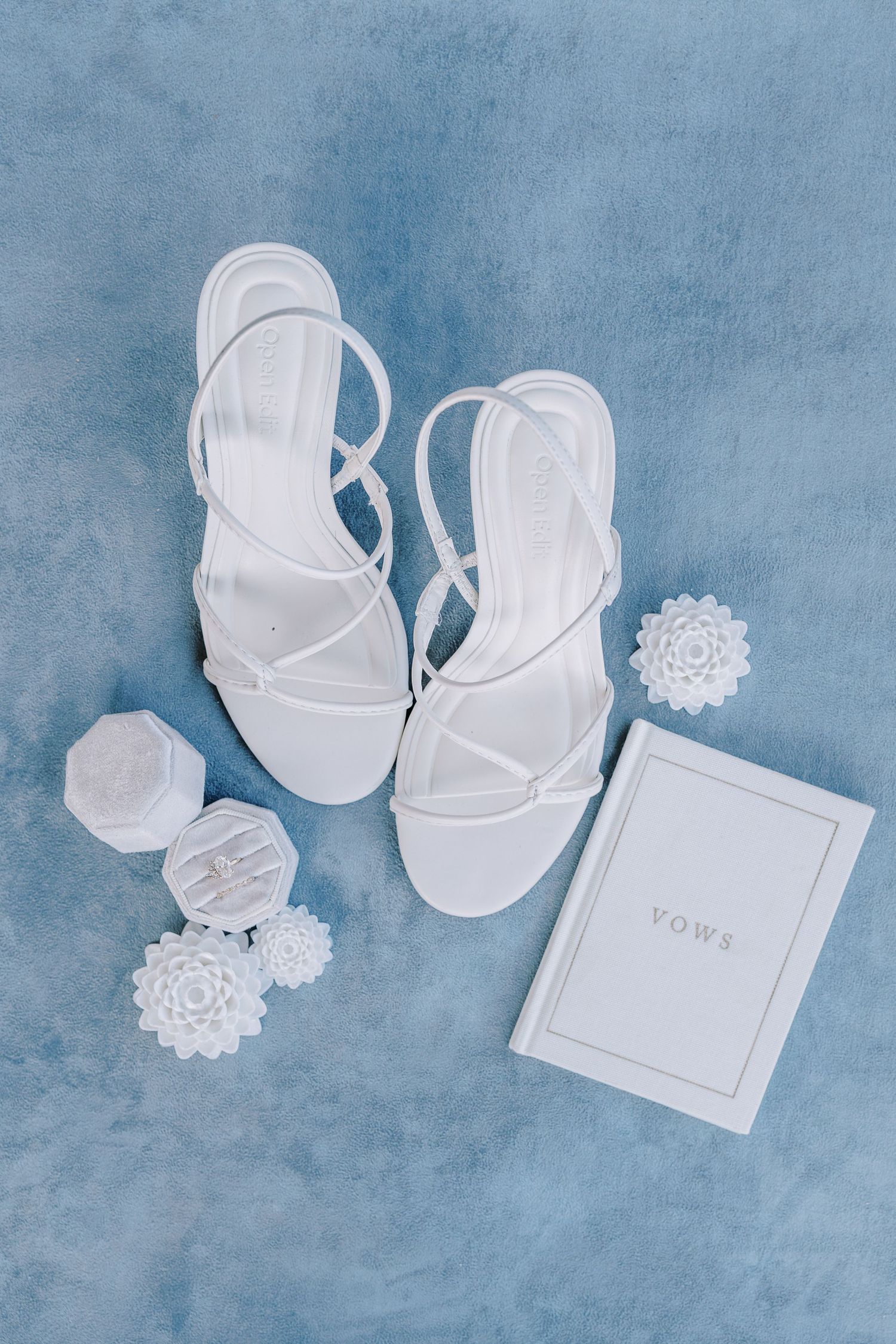 White paper wedding invitations and delicate lace doilies arranged on light blue textured background.