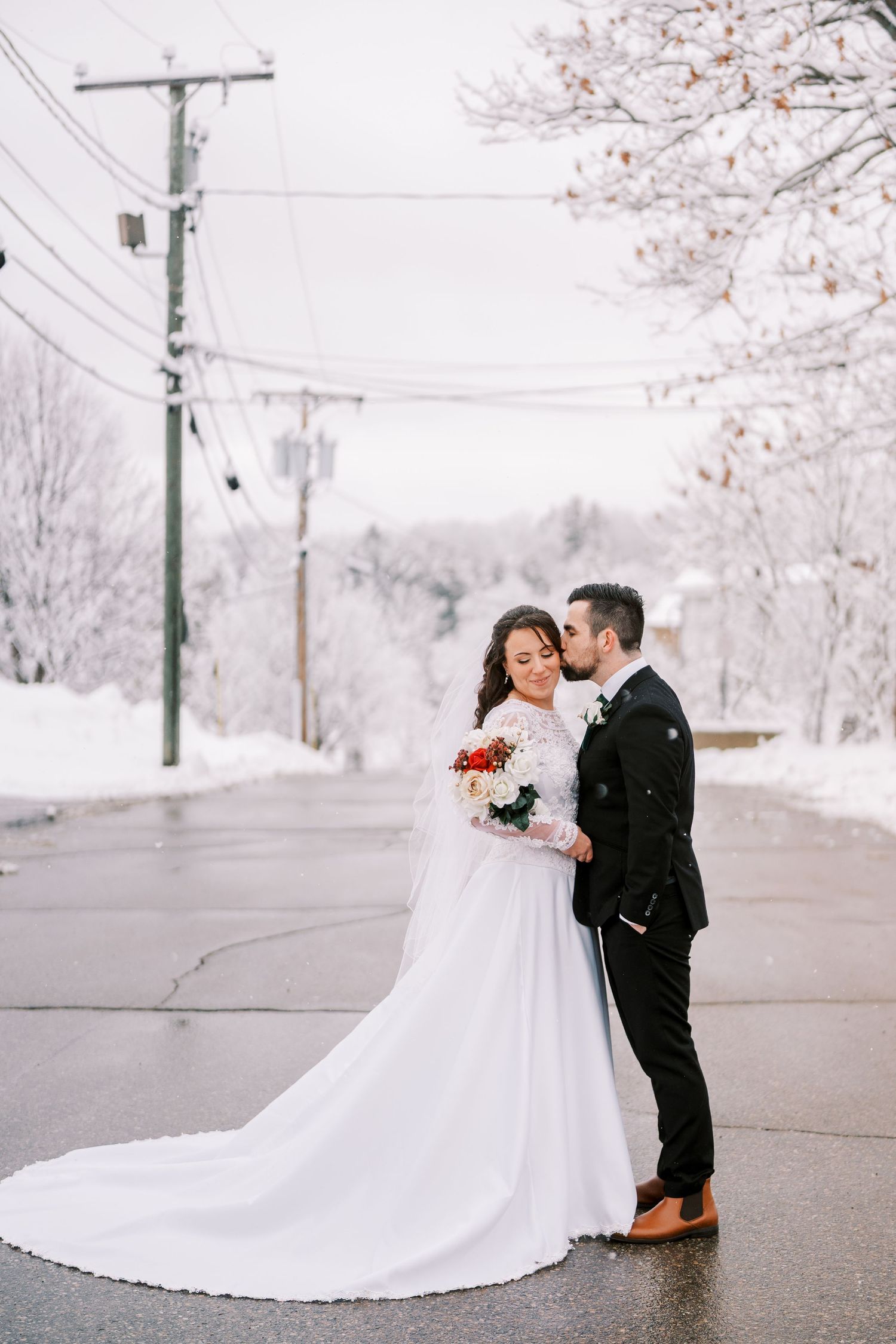Romantic winter wedding portraits with snow-covered cherry blossoms in the background.