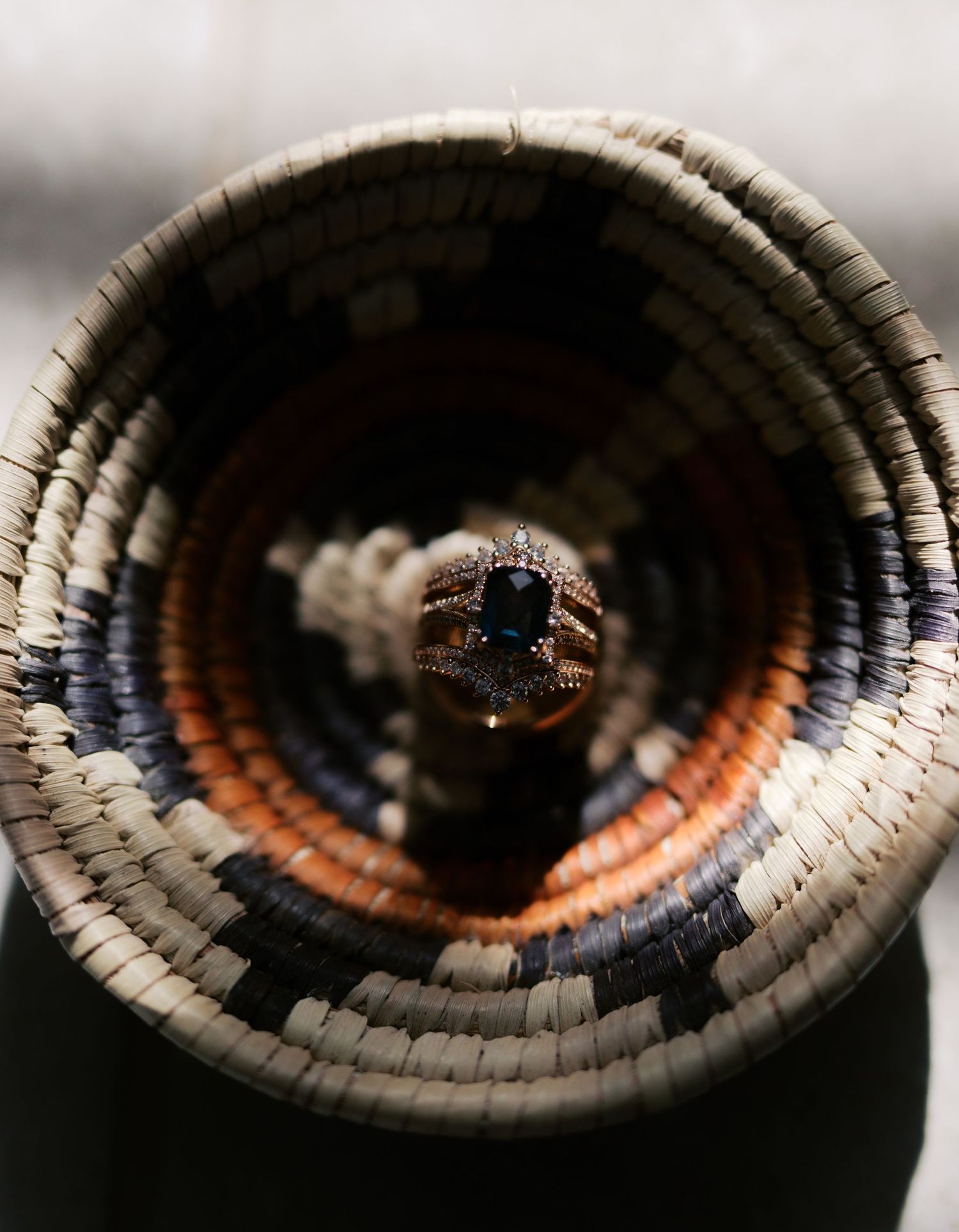Ring photographed inside a handwoven Native American basket with concentric circular patterns in black, white and orange.