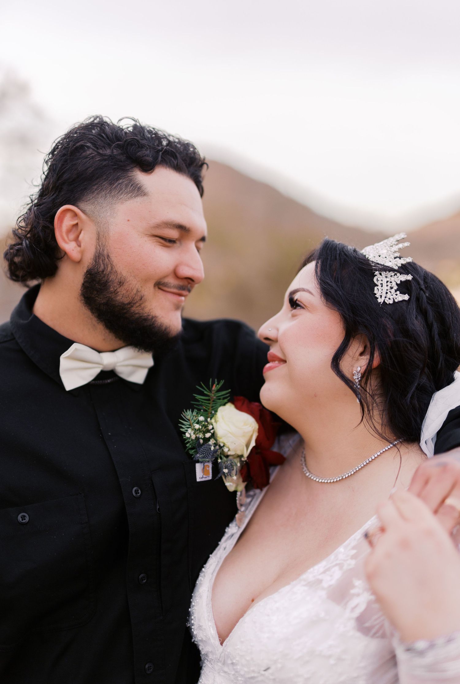 A romantic wedding photo of a couple sharing an intimate moment, with the bride wearing a sparkly hair accessory and white dress.