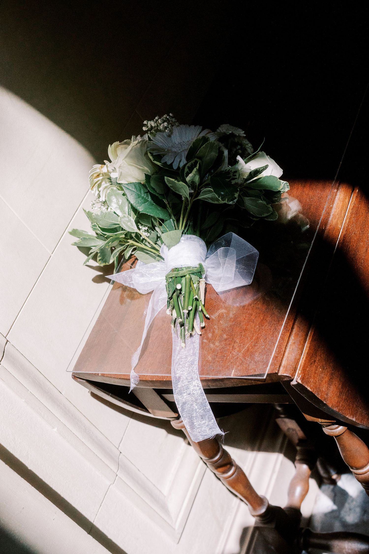 Wedding veil and floral details draped over a wooden surface in dramatic lighting.