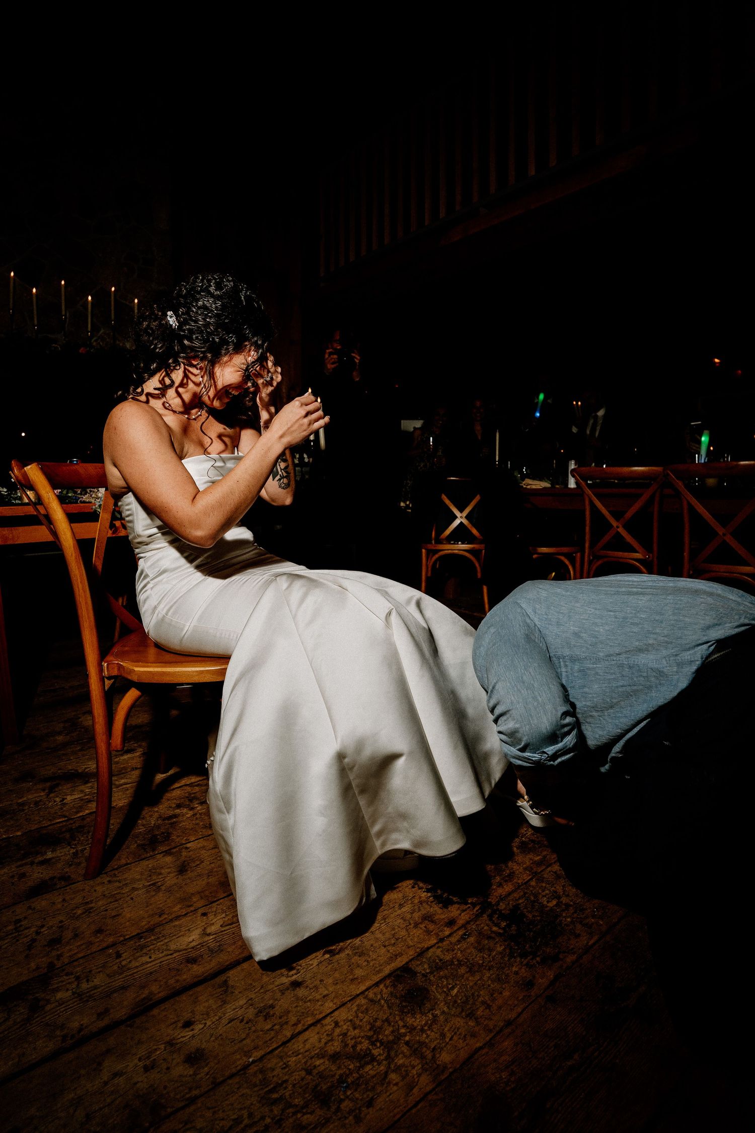 Couple in wedding attire shares an intimate dip dance on a rustic wooden floor at night.