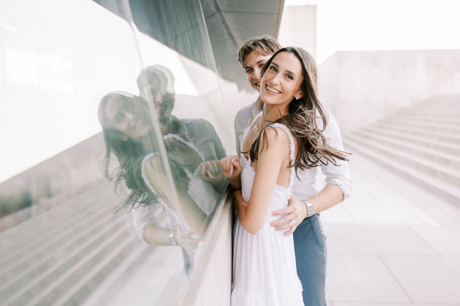 Romantic couple embracing against white architectural background during photo session.