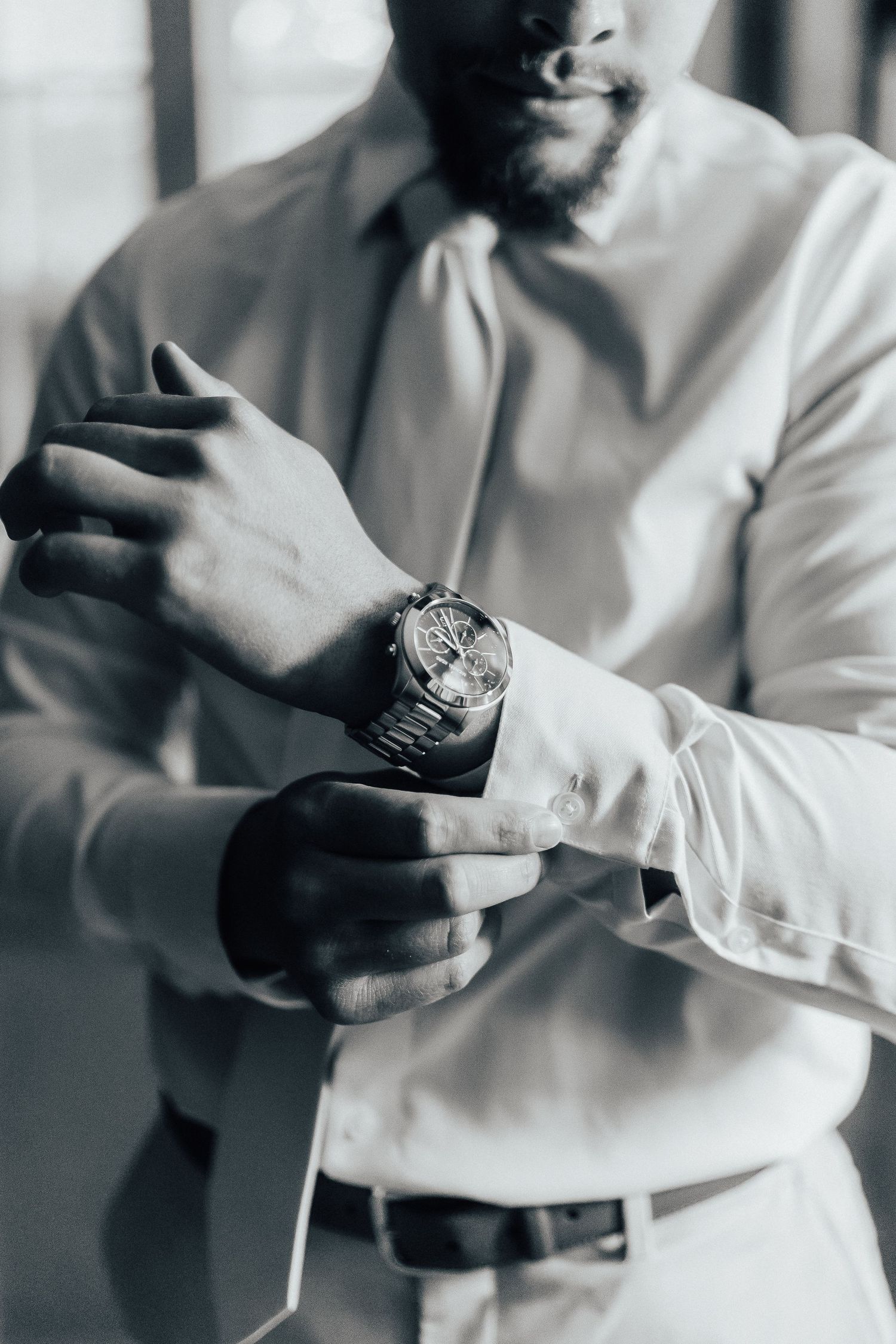Close-up of a silver watch on wrist with white dress shirt sleeves.
