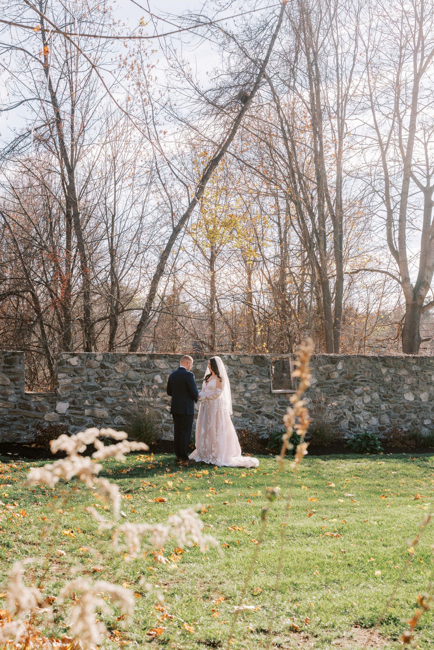 A sequence of four photos showing a person in a dress twirling and dancing on a grassy lawn near a stone wall in autumn.