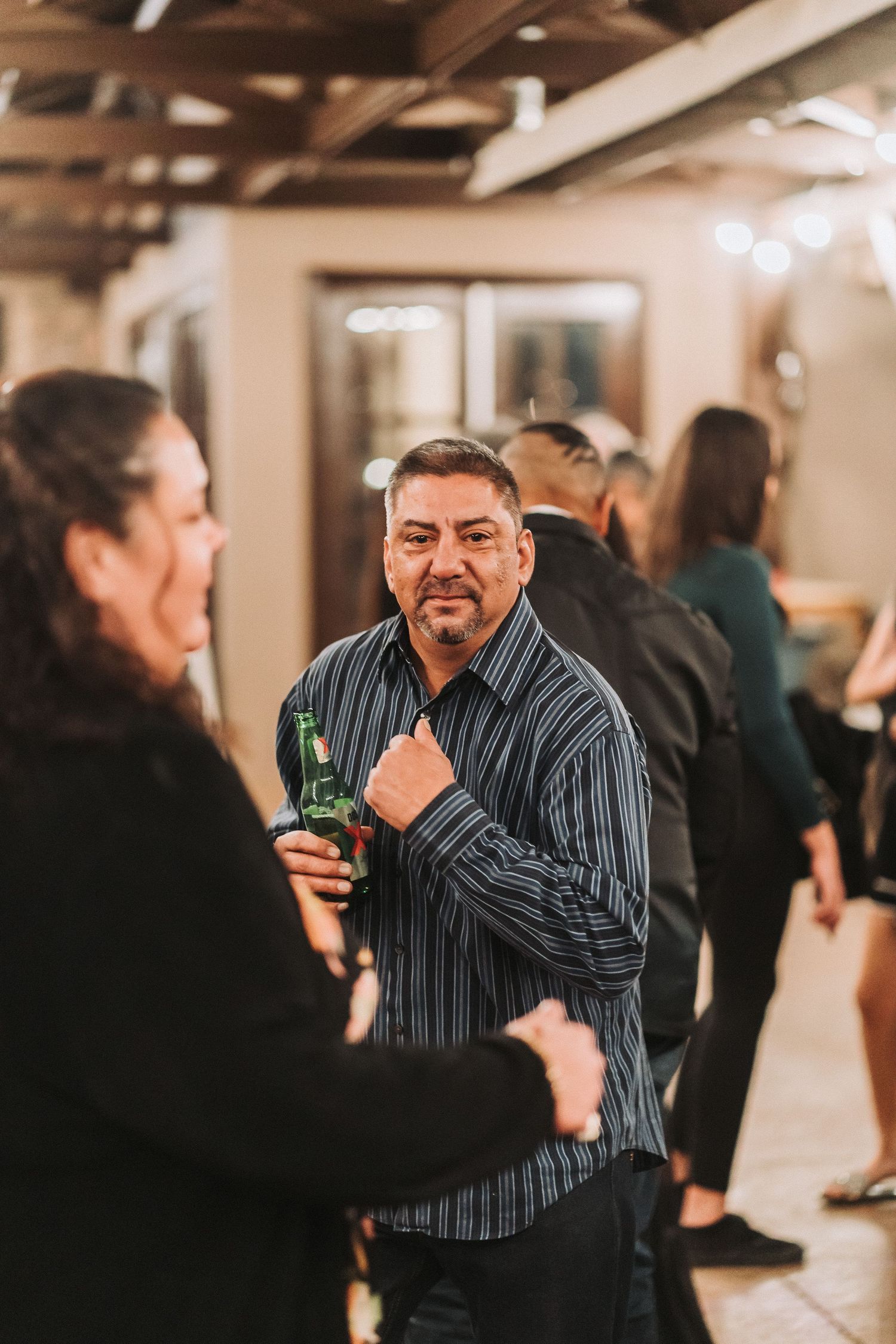 People socializing and having drinks at an indoor gathering with warm lighting and casual atmosphere.