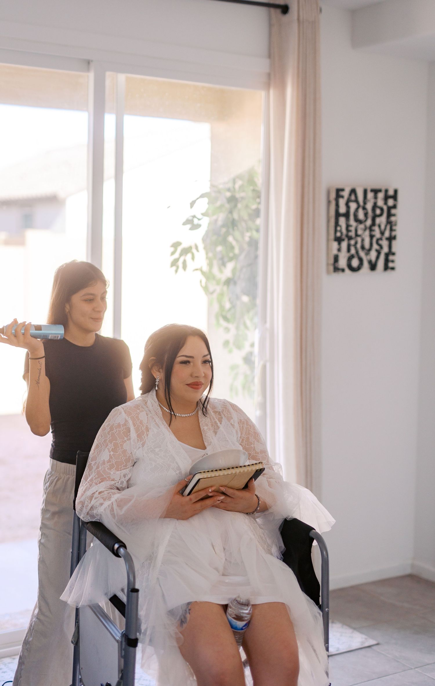 A bridal preparation scene in a bright room with a wedding dress and text wall art reading 'Faith Hope Love'.