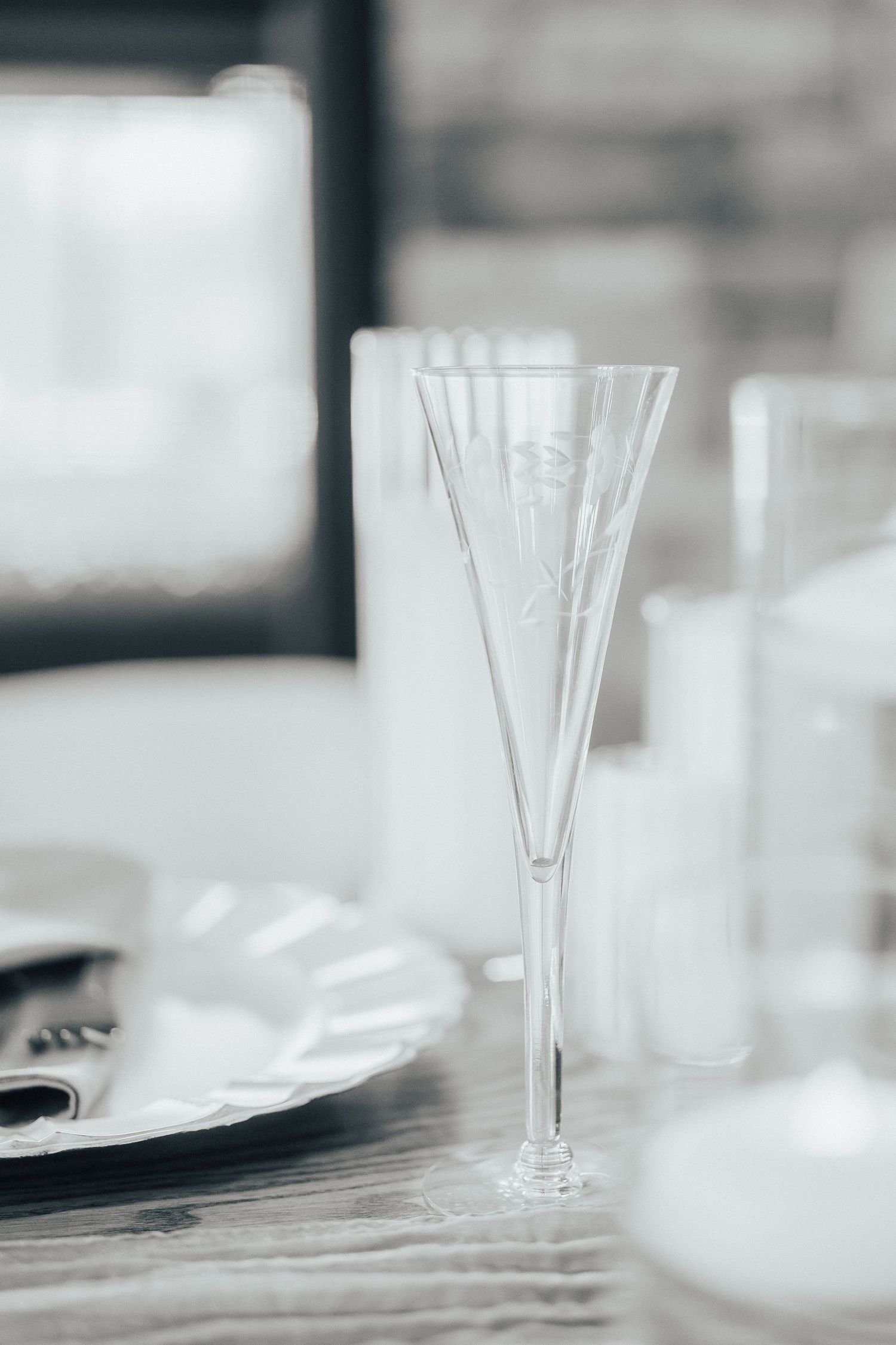 Crystal wine glasses arranged in a row on a wooden table with soft focus and minimalist aesthetic.