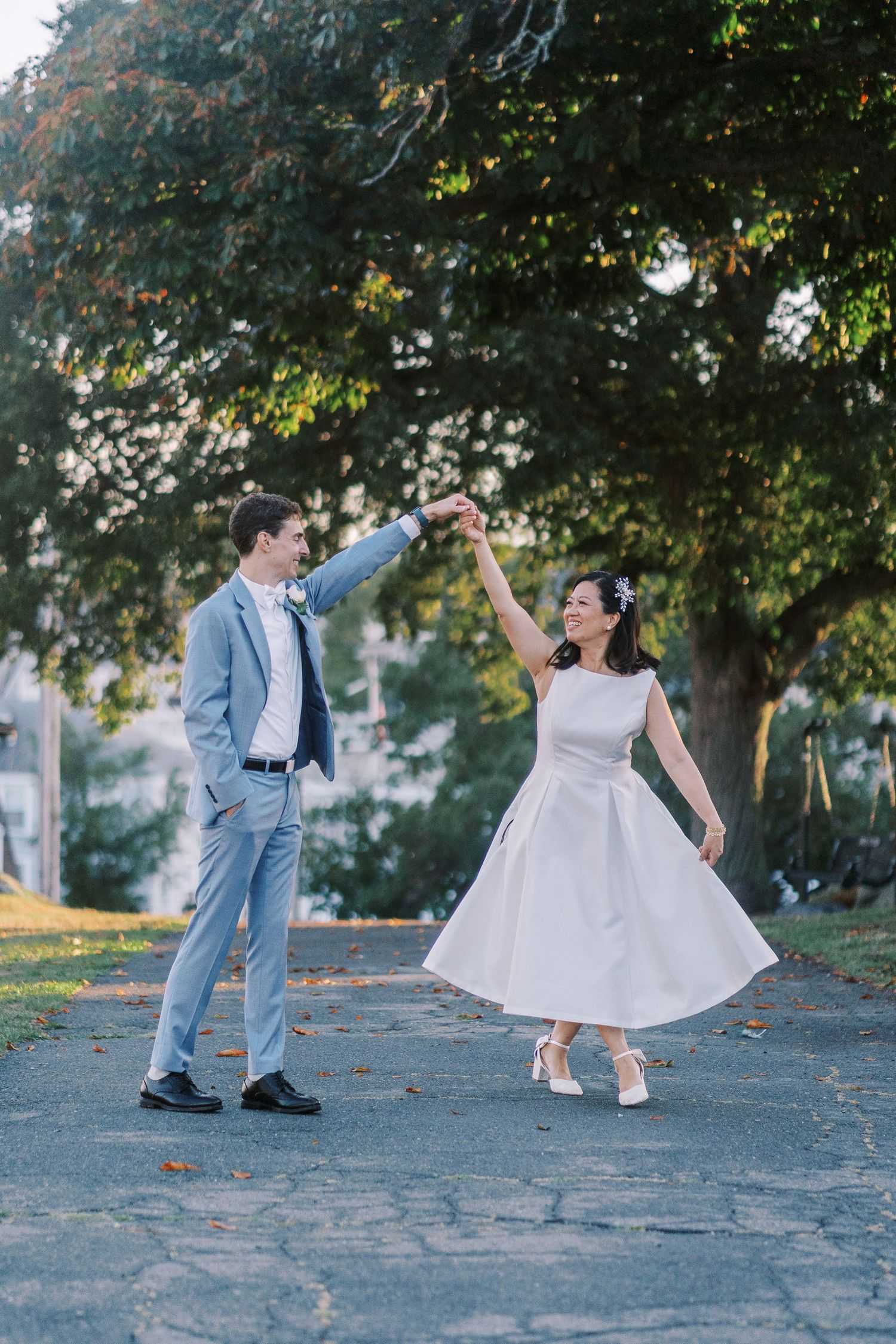 Playful wedding photos on a cobblestone path showing dance-like movements between newlyweds.