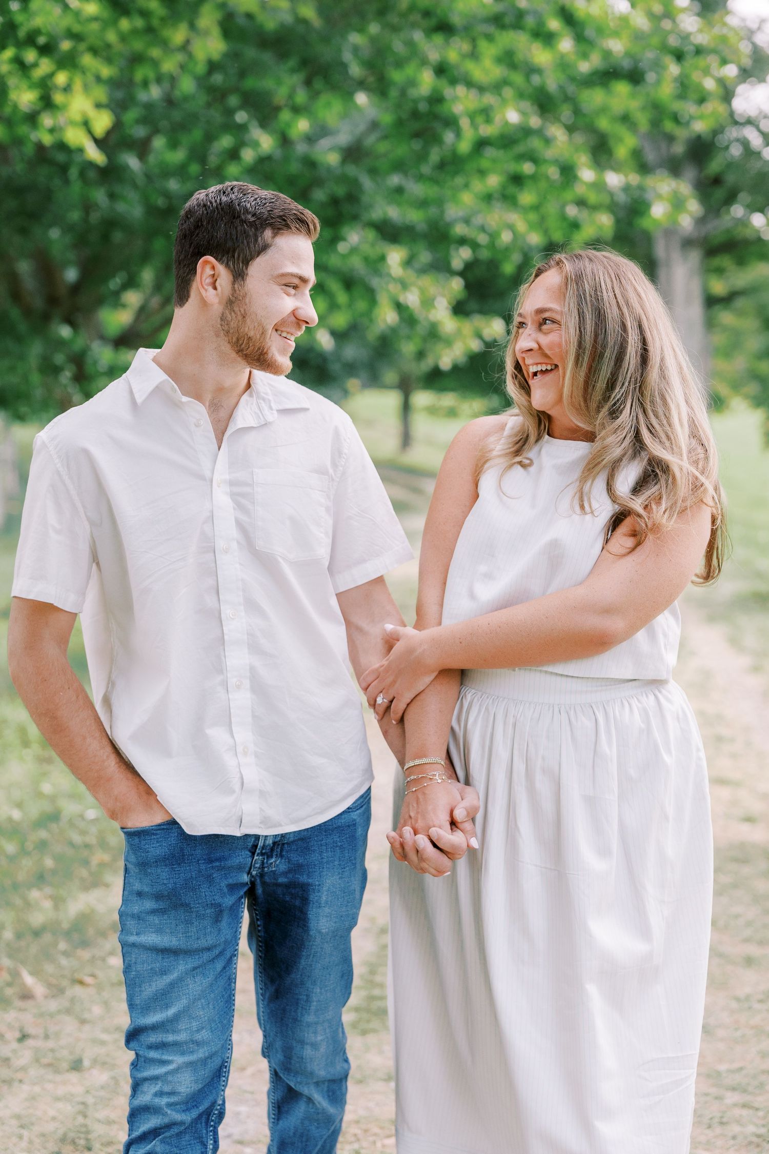 A couple in coordinating white outfits sharing playful moments together outdoors.