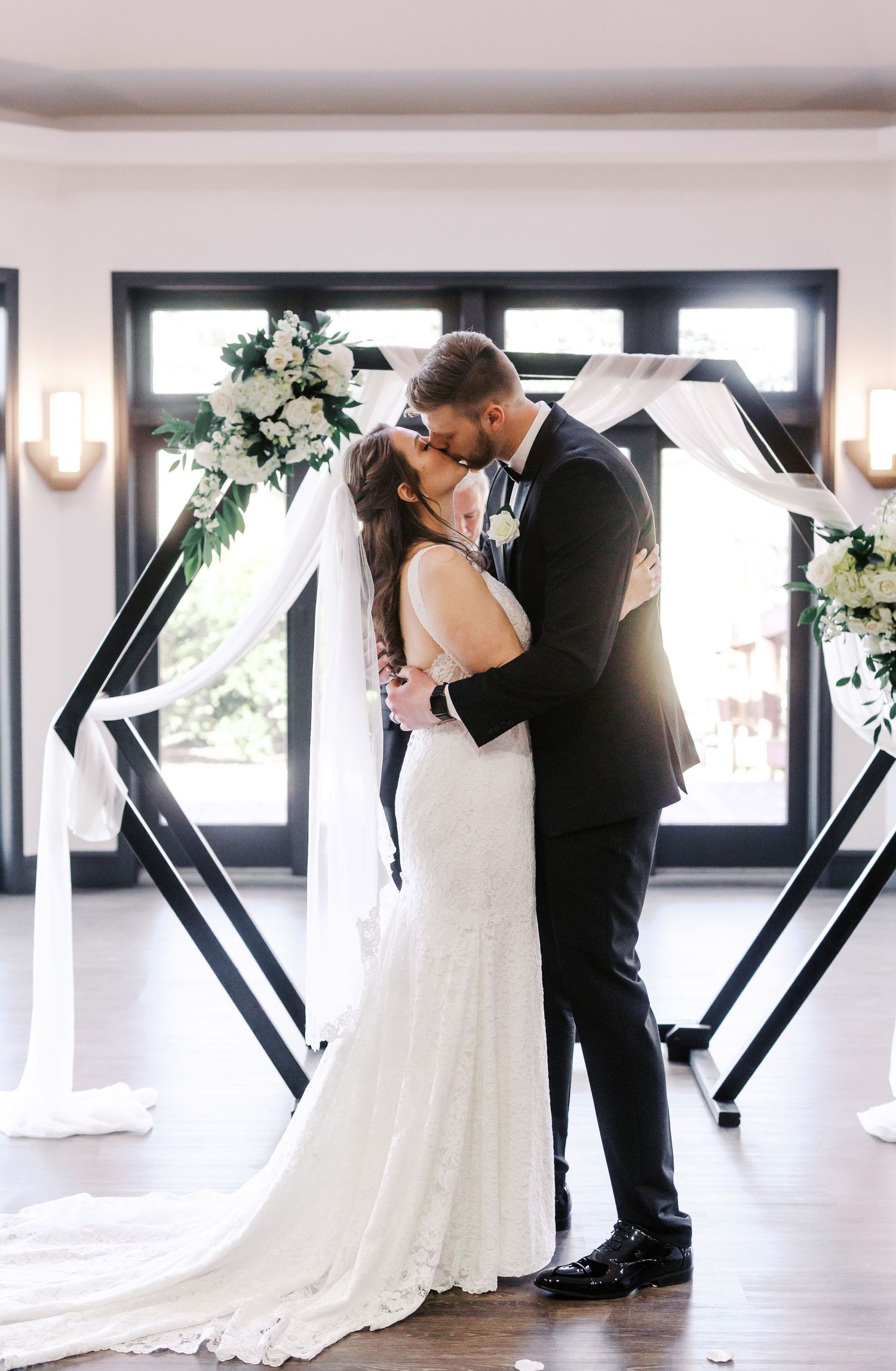 Romantic first dance scene with geometric black backdrop and white floral arrangements.