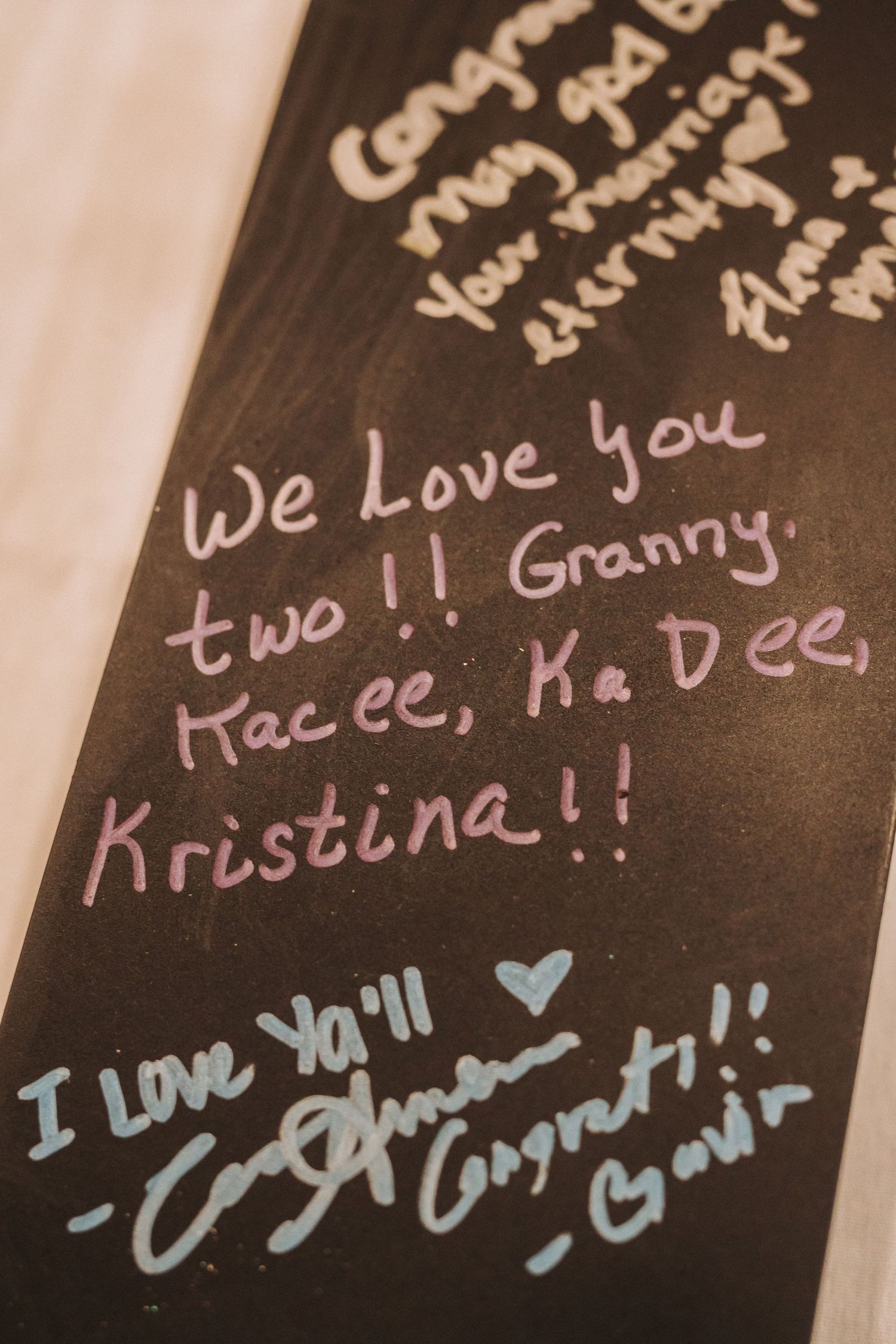Handwritten messages of love and names written in white ink on a dark surface.