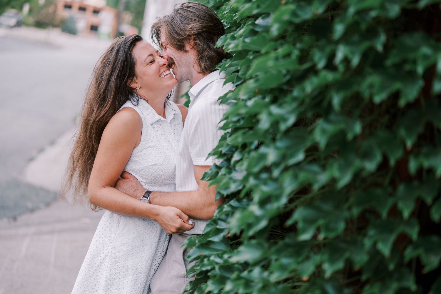 A couple shares tender moments together among green leafy trees in an outdoor setting.