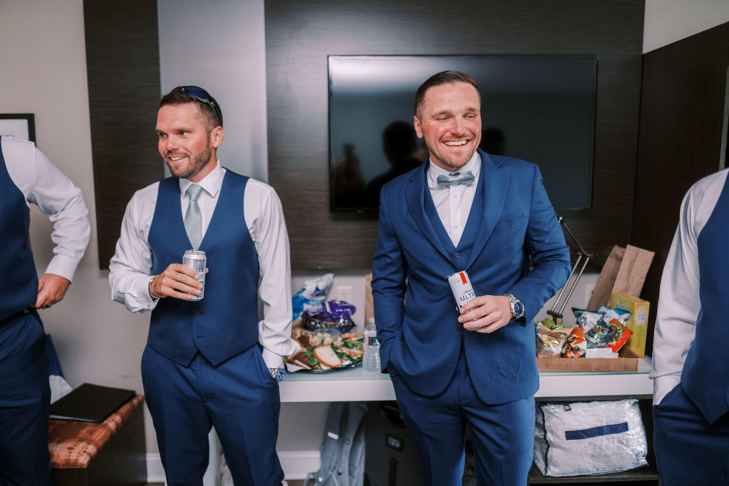 A group in blue suits and formal attire gather around a table with drinks and food at a social event.