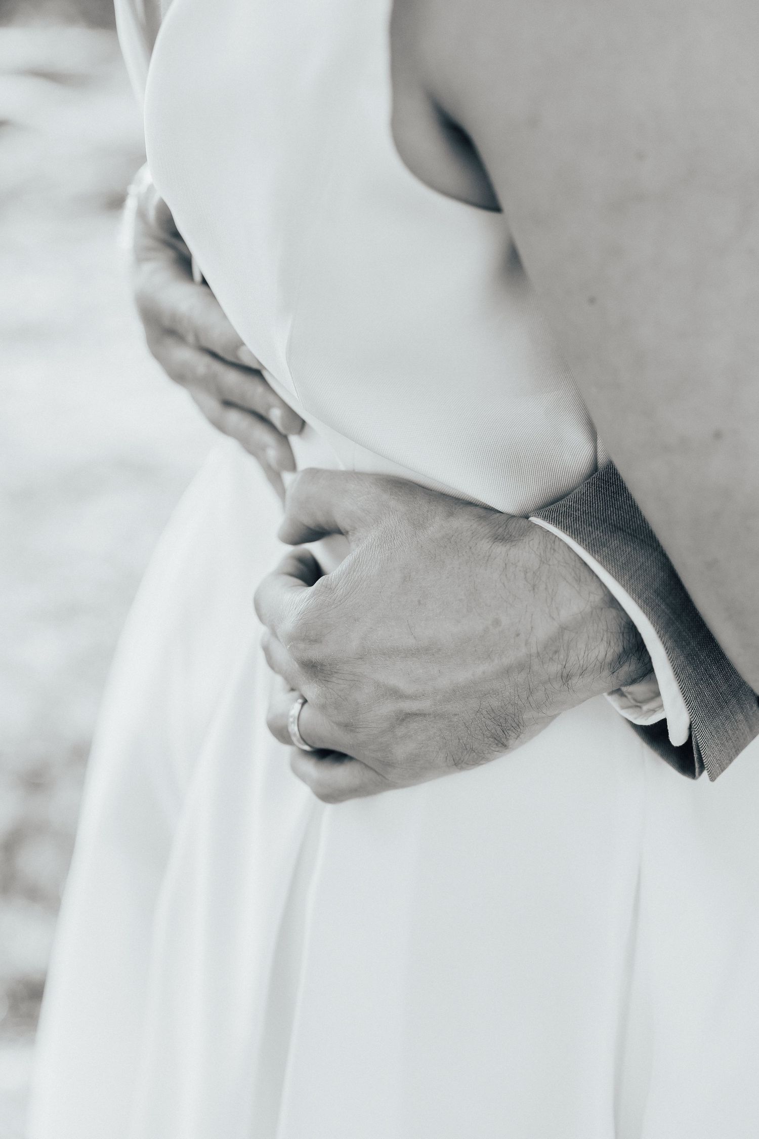 Black and white detail shot of hands adjusting white formal dress fabric.
