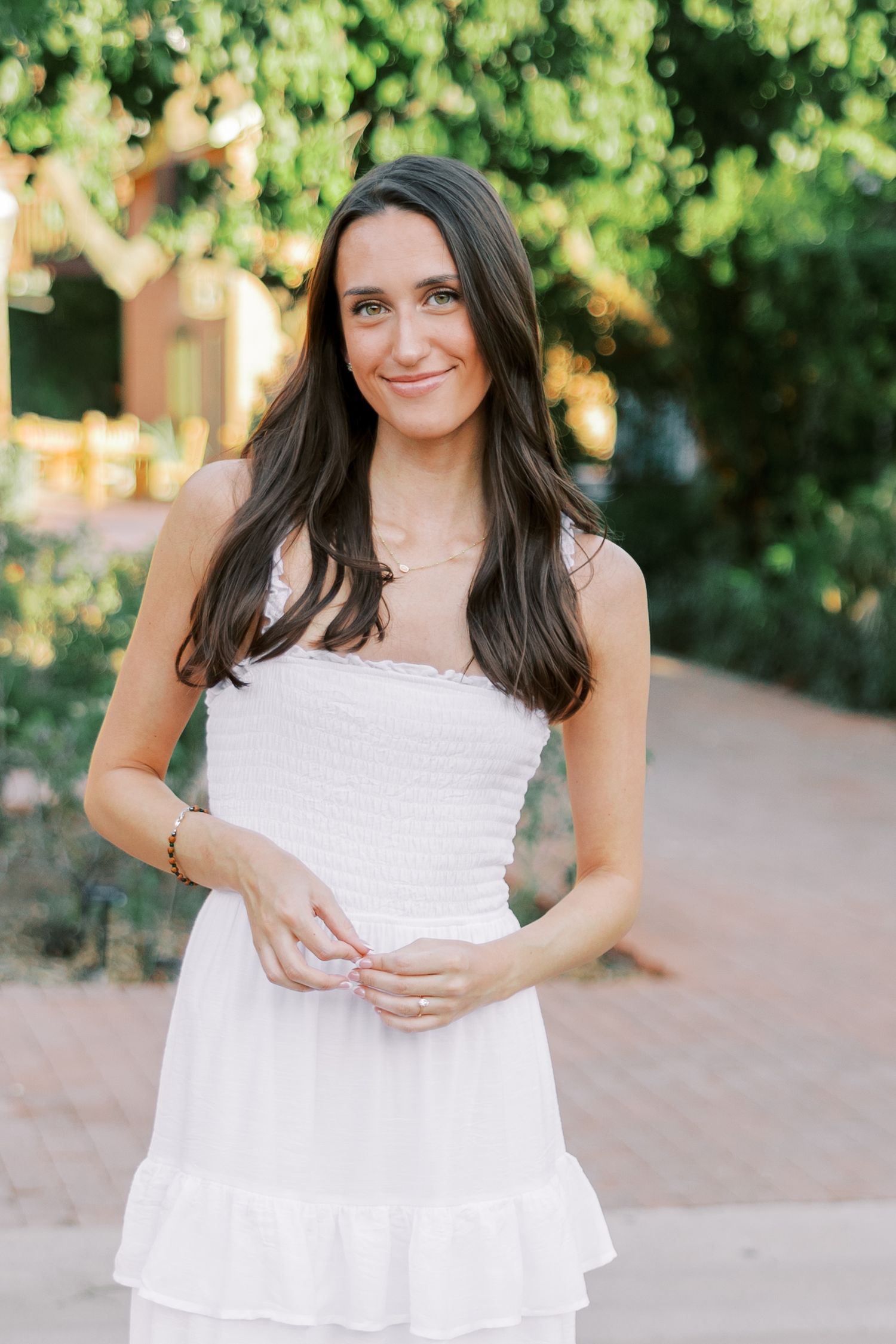 A person in a white summer dress poses outdoors in a series of four casual portrait shots against a green background.